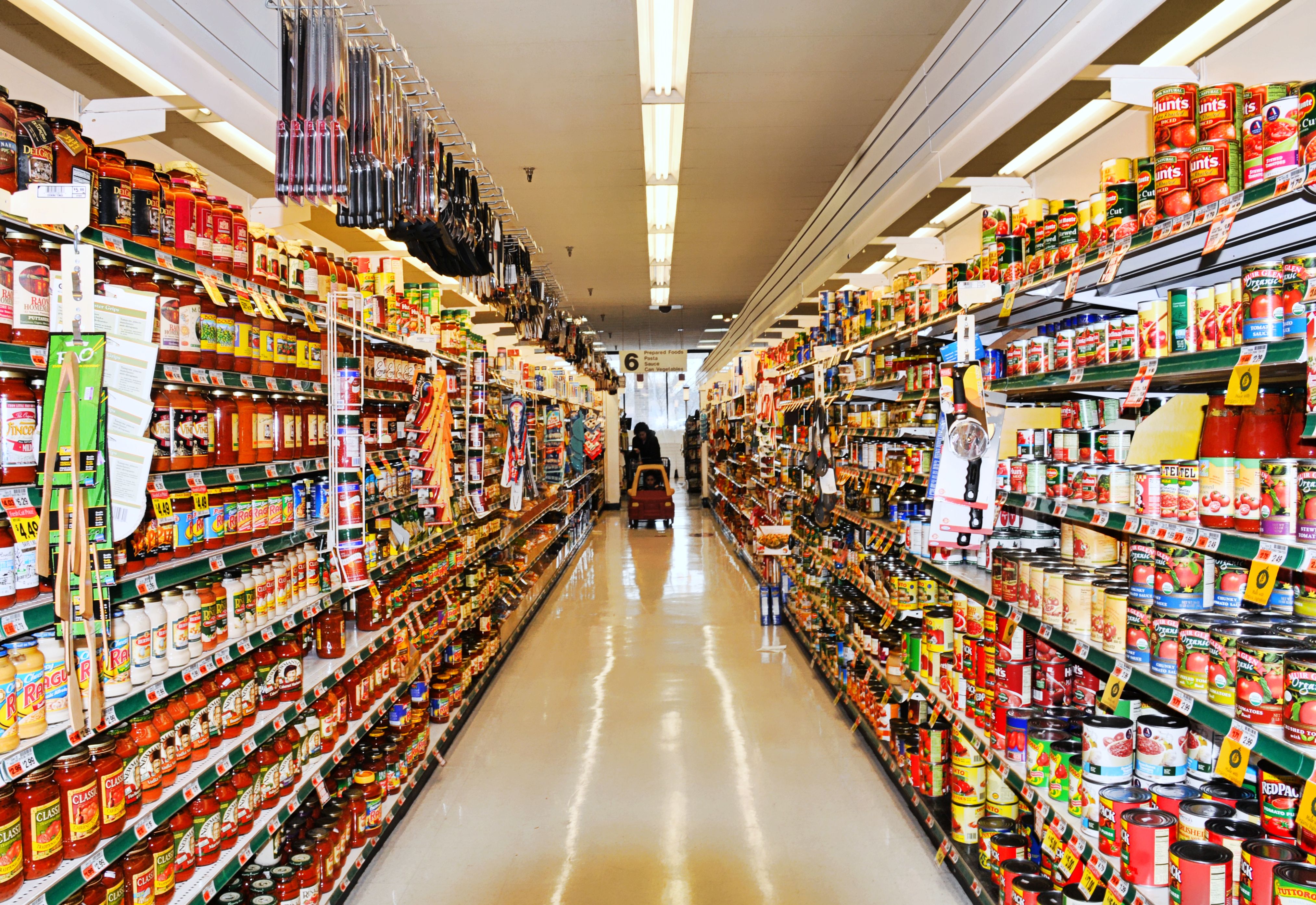 Aisle at supermarket with shopper and shopping cart
