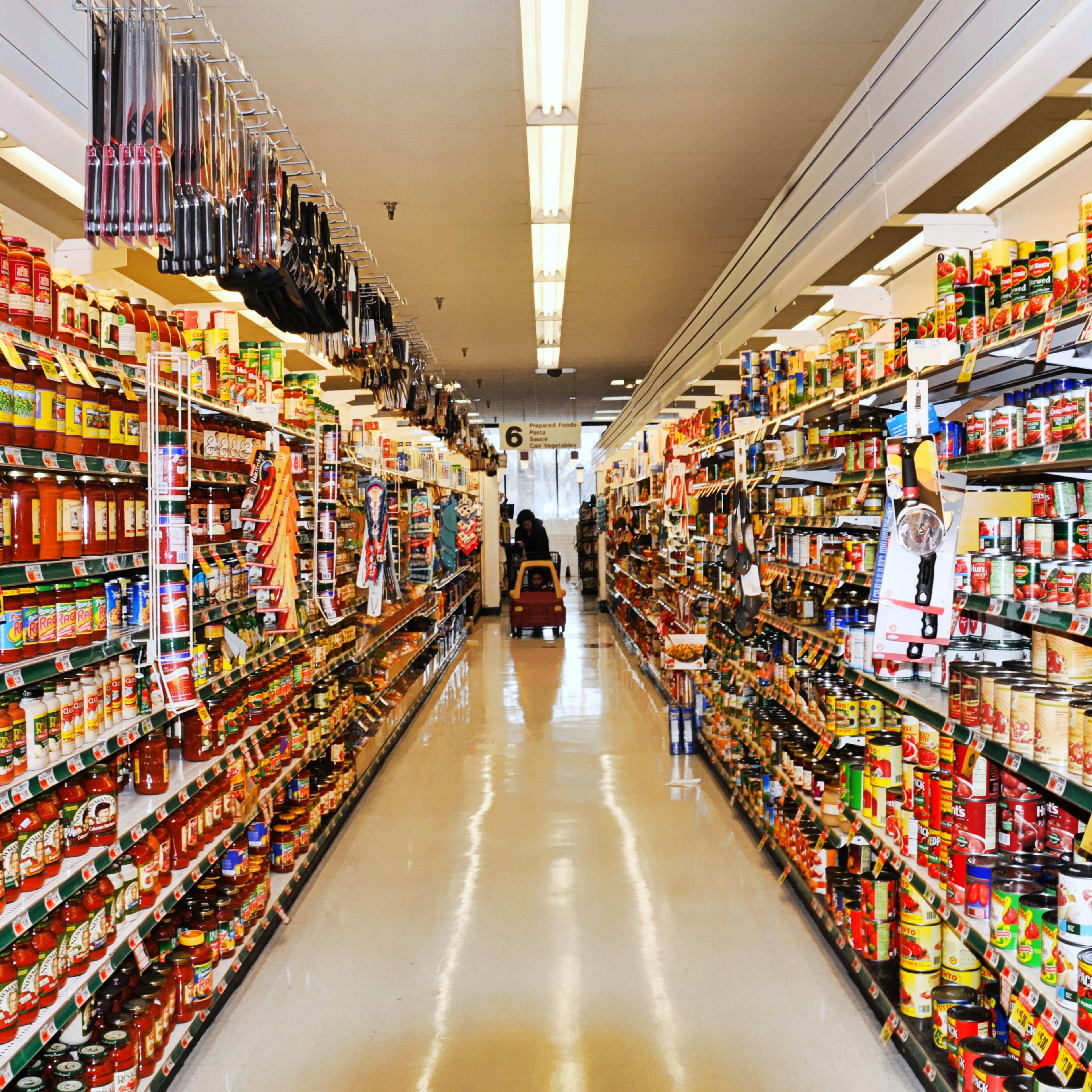 Aisle at supermarket with shopper and shopping cart