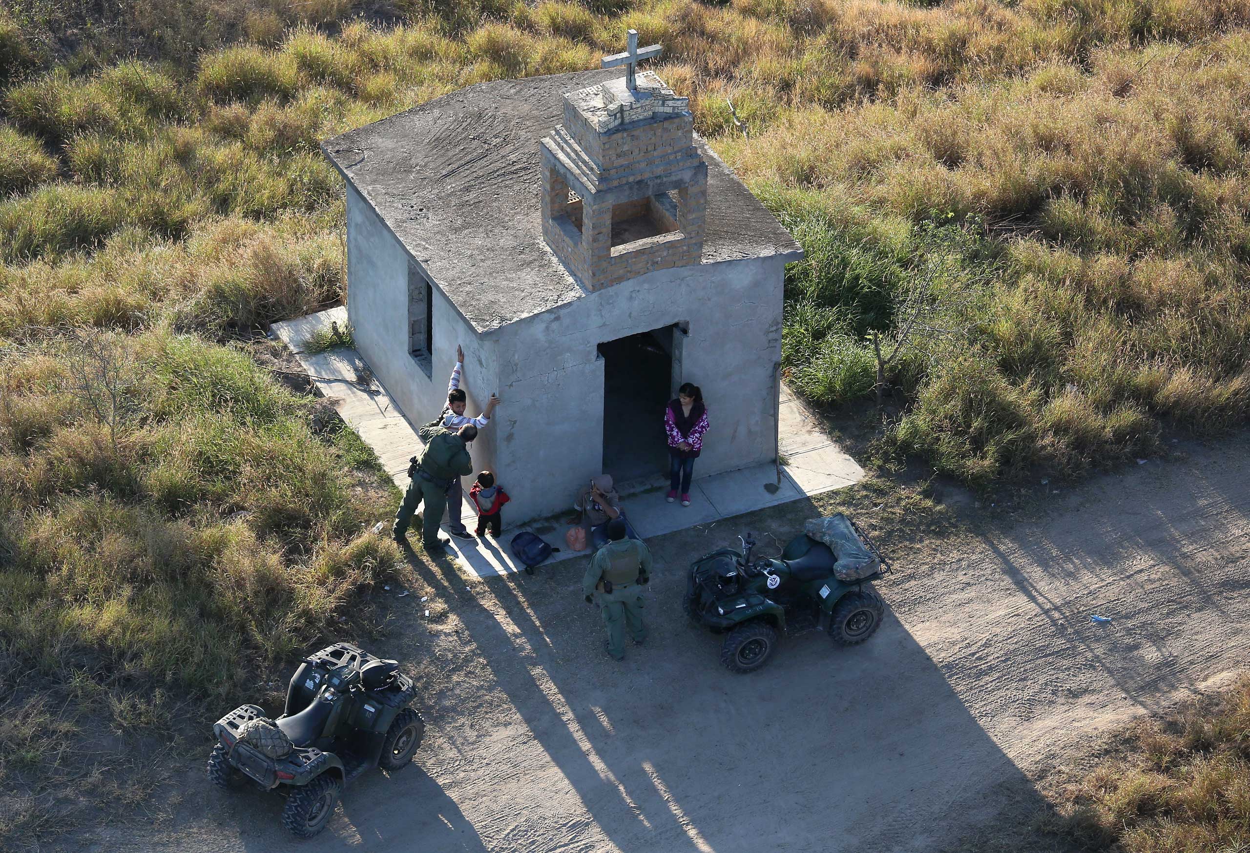 U.S. Border Patrol agents search a migrant family after they crossed the U.S.-Mexico border near Rio Grande City, Texas, on Dec. 9, 2015.