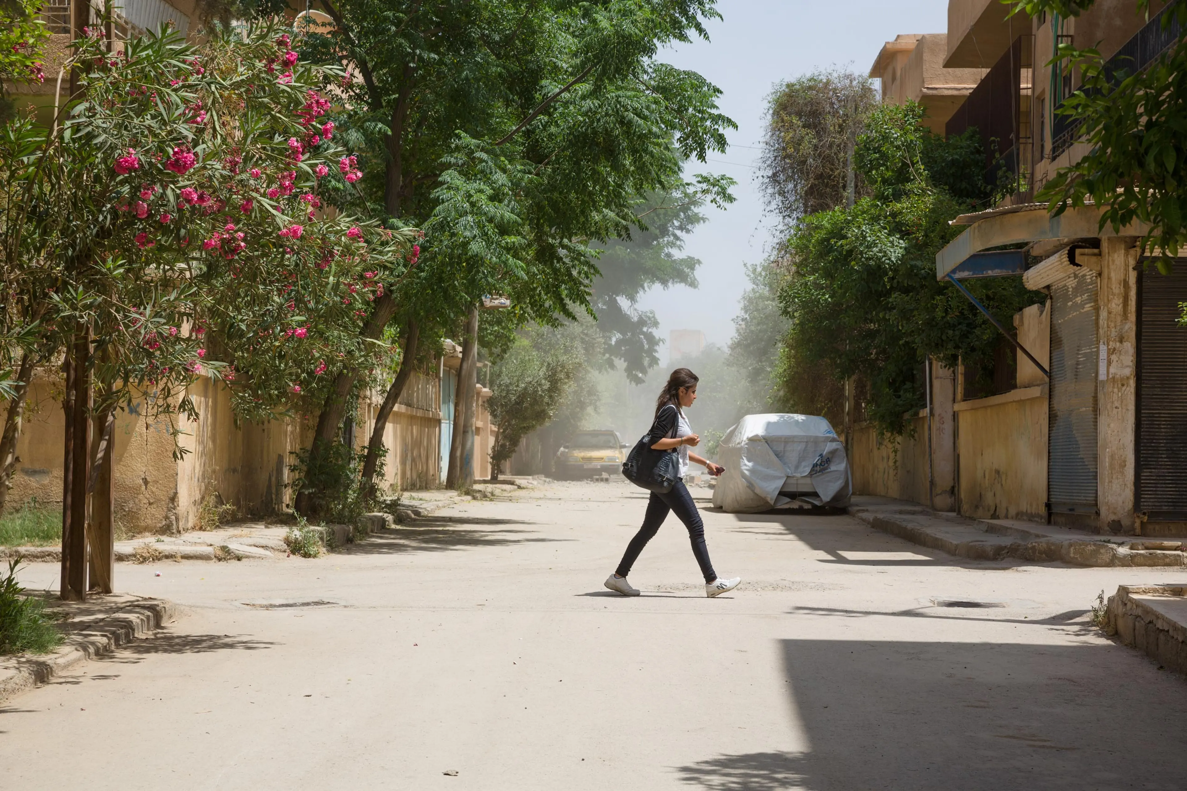 A young woman crosses a street in Ghazi Ayaash, a residential neighborhood of Deir-ez Zor a few hundred feet from the frontline, after a mortar attack from an ISIS position. The city is an outpost of modernity surrounded by ISIS-controlled areas where strict Islamic law is enforced, May 20, 2015.
