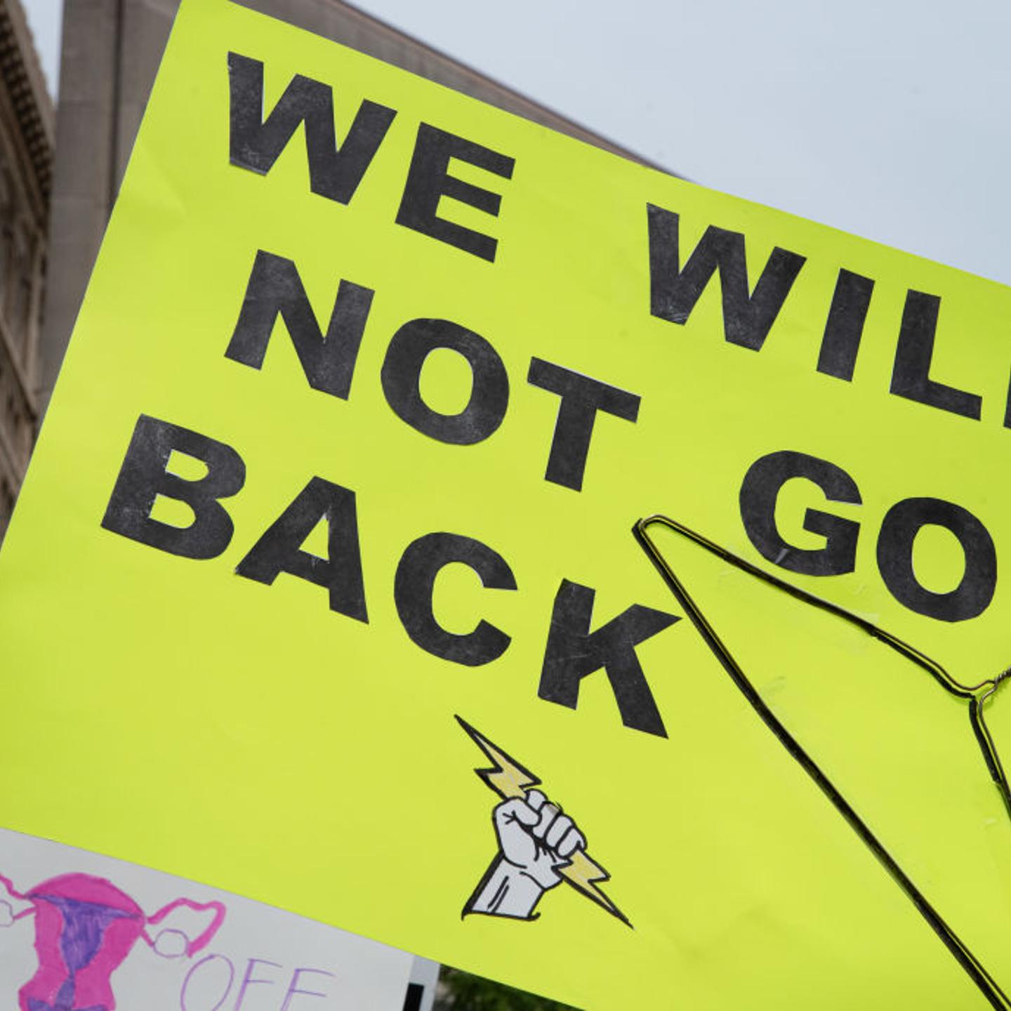 A protester holds a placard that says "We will not go back"