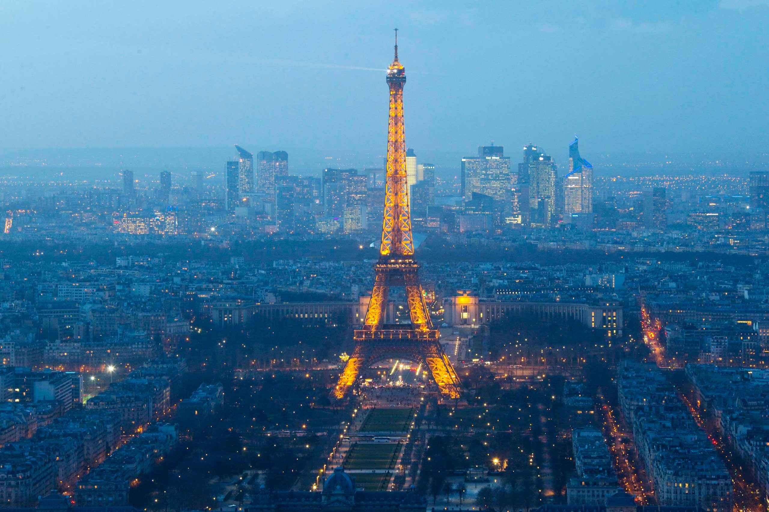 A view shows the illuminated Eiffel Tower and La Defense business district in Paris, Feb. 24, 2015.