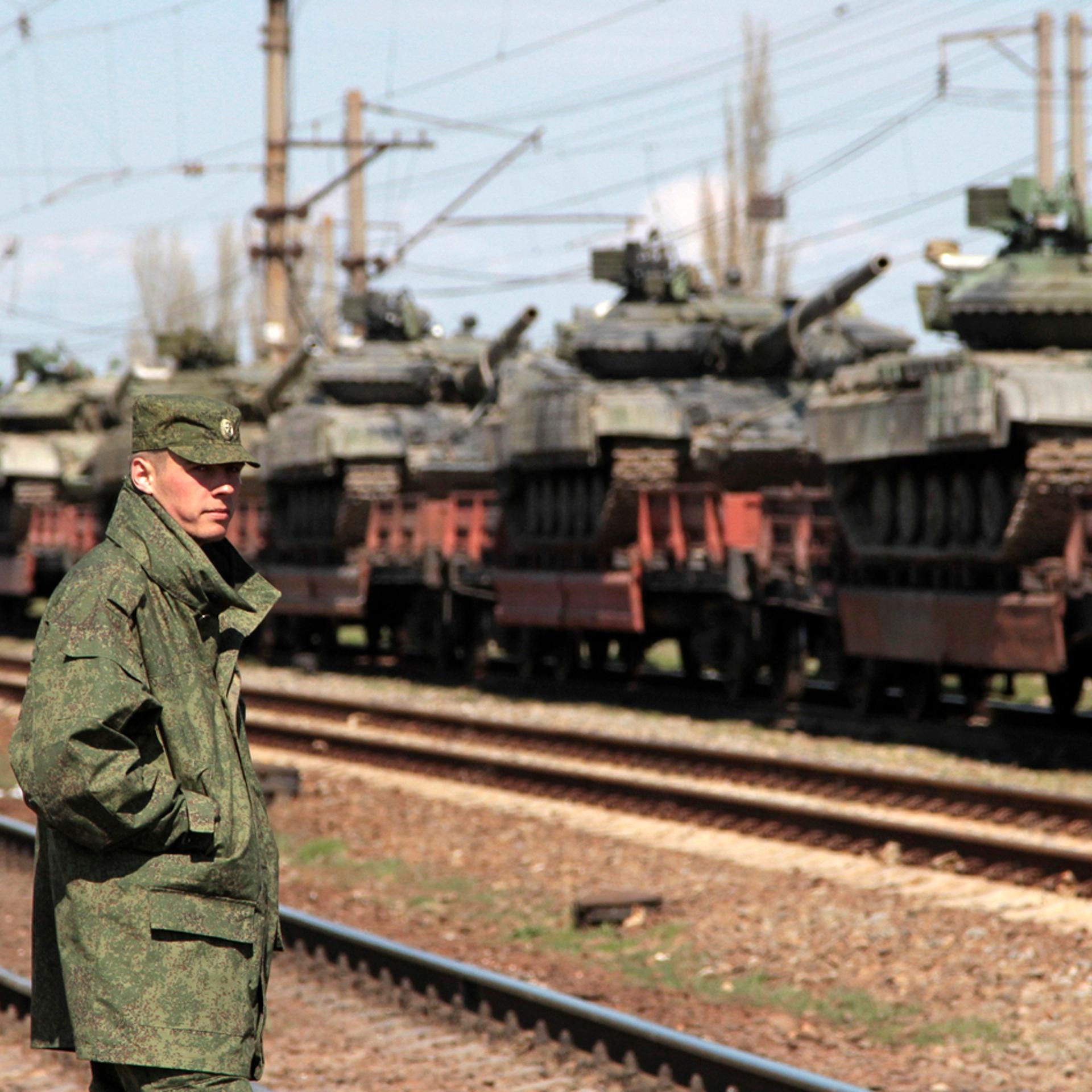A Russian serviceman stands near Ukrainian tanks on freight cars before the departure from Crimea to other regions of Ukraine in the settlement of Gvardeiskoye near the Crimean city of Simferopol