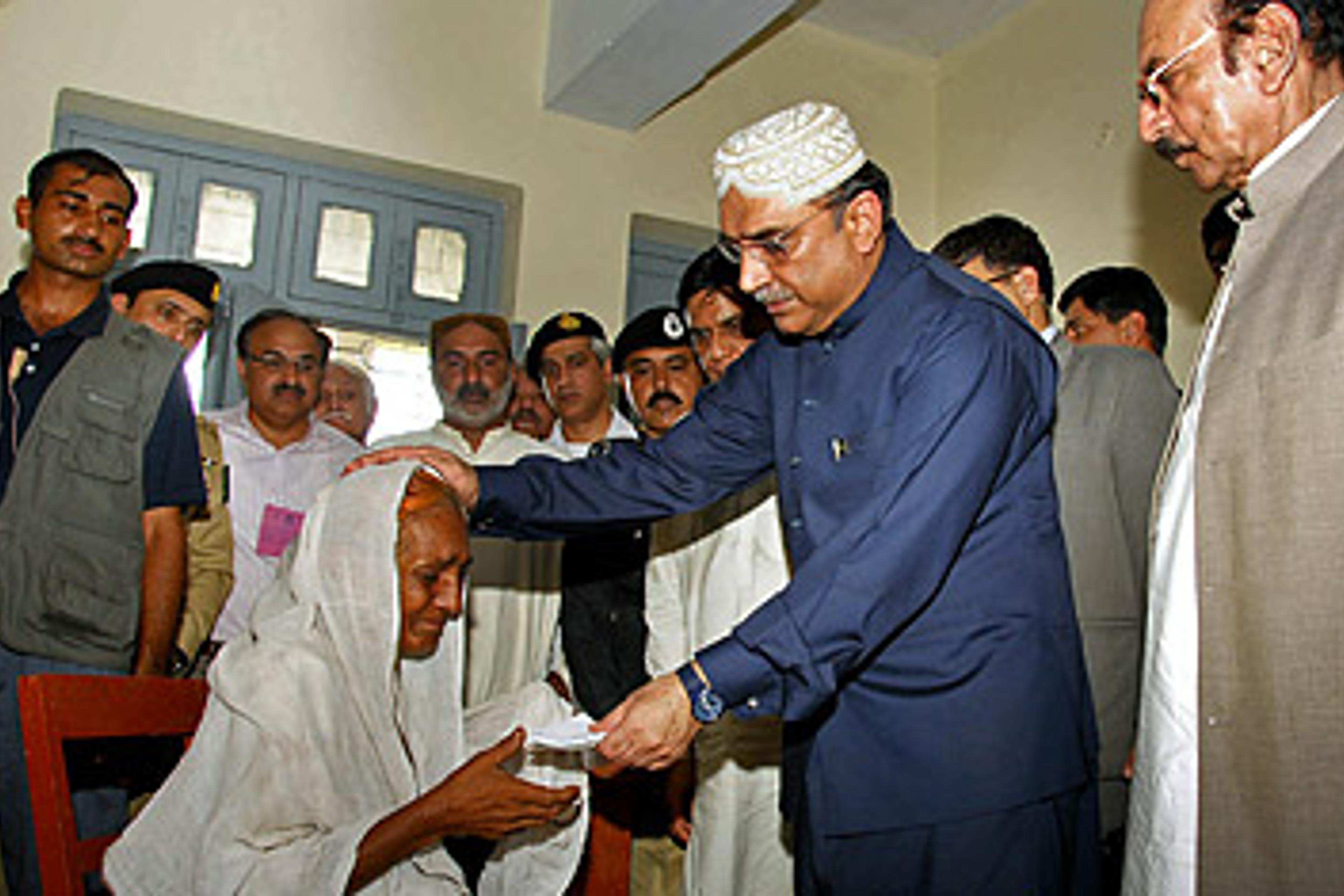 Pakistani President Asif Ali Zardari presents a check to a flood survivor during a visit to a relief camp in Sukkur