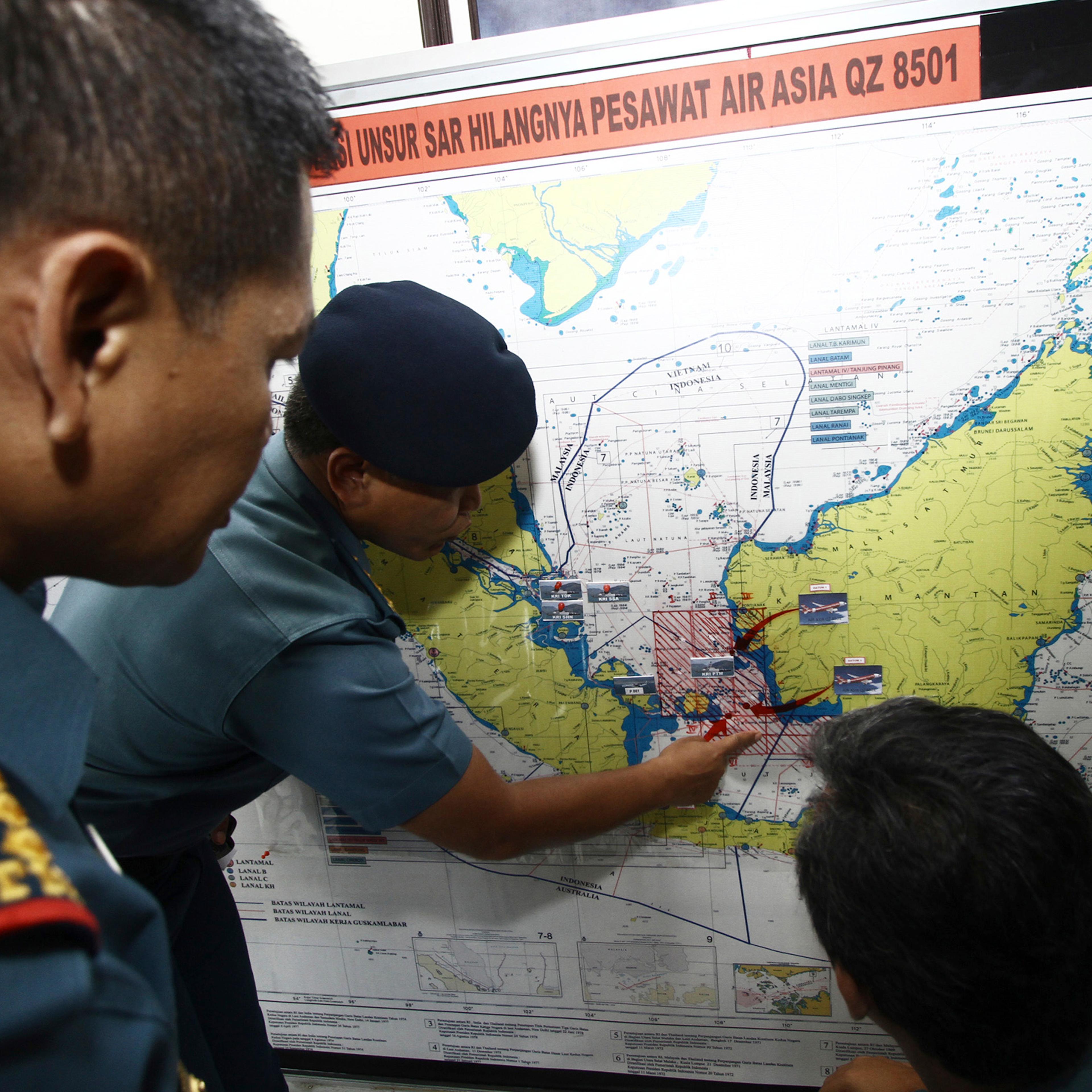 Navy soldiers work on a map of Indonesia monitoring all Navy ships from Indonesia, Singapore, and Malaysia involved in the joint search and rescue operation for AirAsia flight QZ8501 at a navy base on Batam island