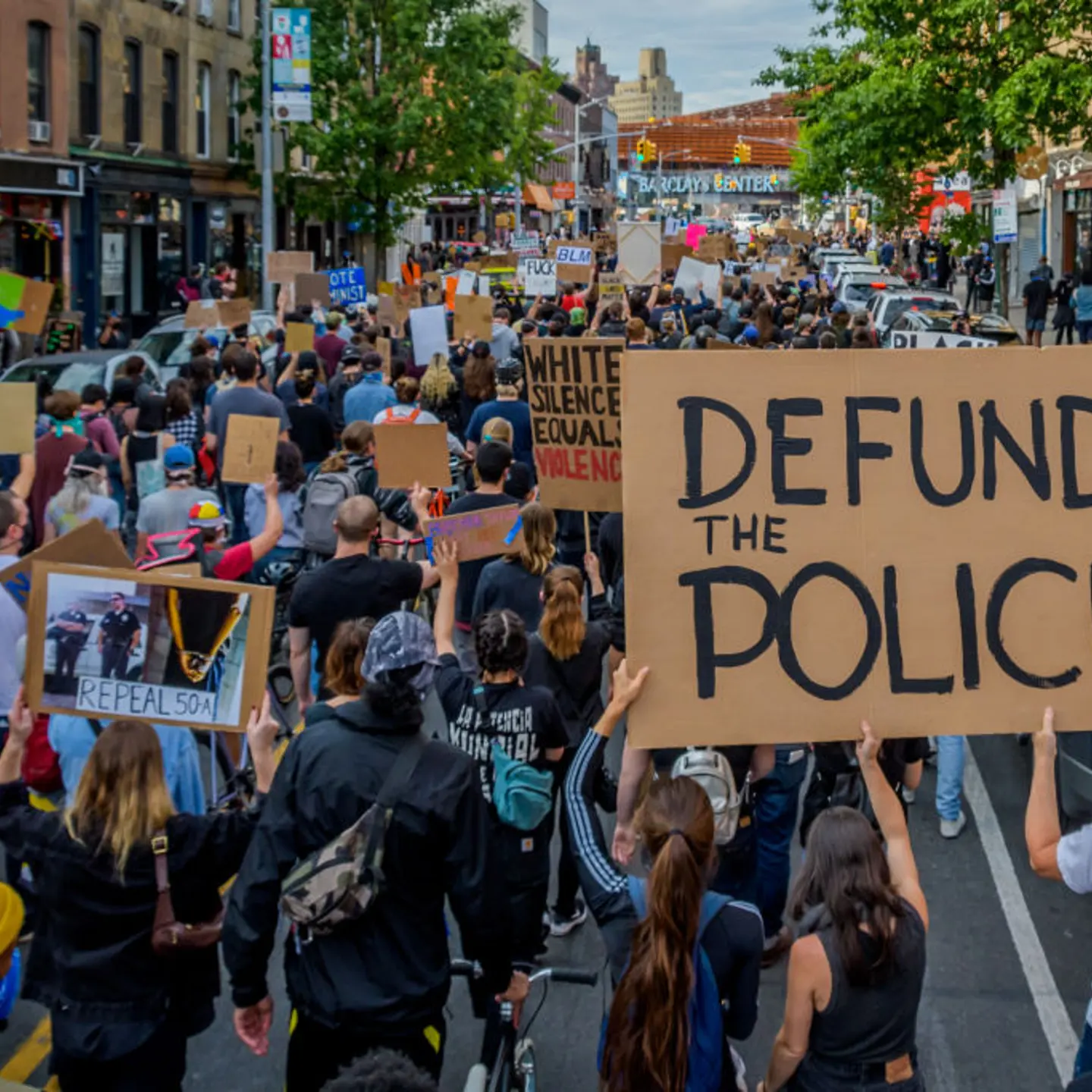 A participant holding a Defund The Police sign at the