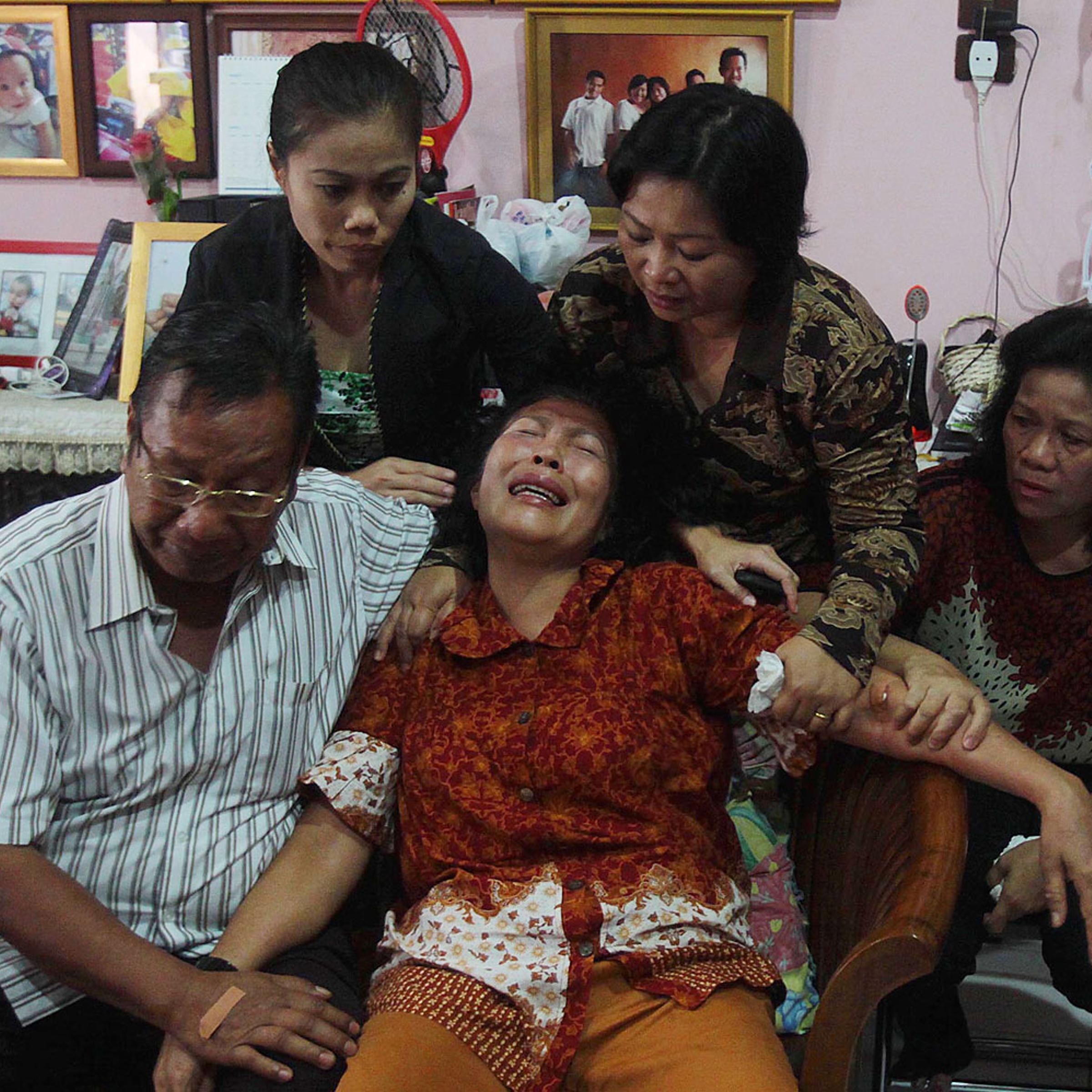 Risman Siregar, left, comforts his wife Erlina Panjaitan, center — both are parents of Firman Chandra Siregar, a 24-year-old Indonesian passenger of Malaysia Airlines Flight 370 — on March 9, 2014, in Medan, Indonesia