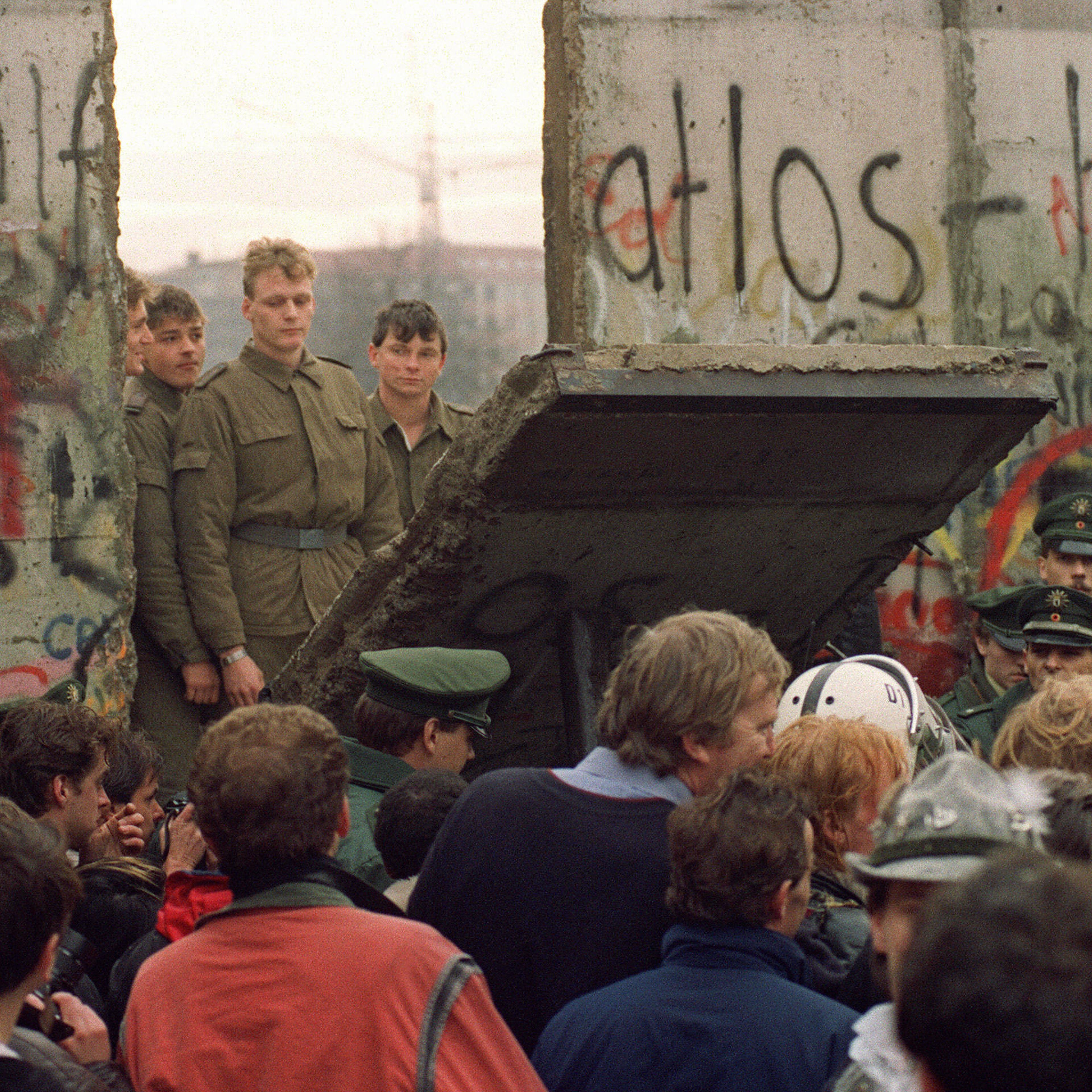 A crowd in front of the Berlin Wall on Nov. 11, 1989 watches border guards demolish a section of the wall in order to open a new crossing point between East and West Berlin in Germany.