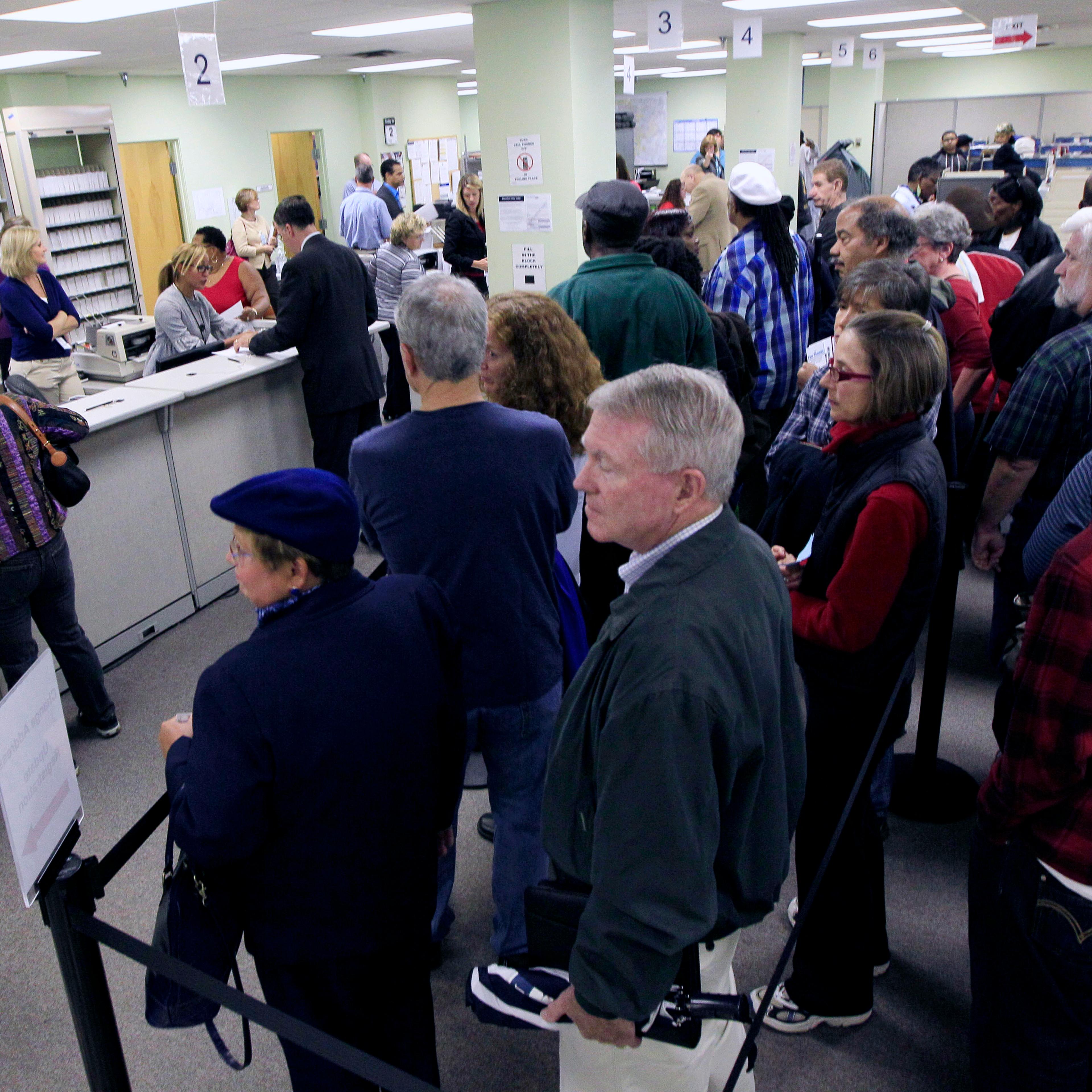 This Oct. 2, 2012 file photo shows voters waiting in line to pick up their ballots inside the Hamilton County Board of Elections after it opened for early voting, in Cincinnati.