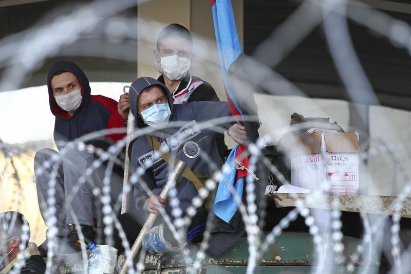 Pro-Russian protesters are seen through barbed wires at a barricade outside a regional government building in Donetsk
