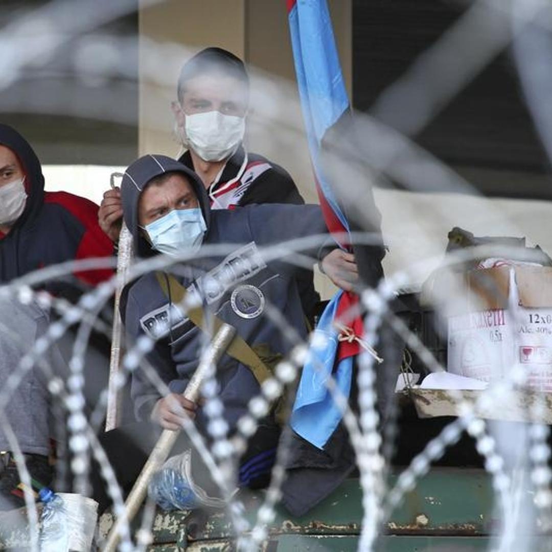 Pro-Russian protesters are seen through barbed wires at a barricade outside a regional government building in Donetsk