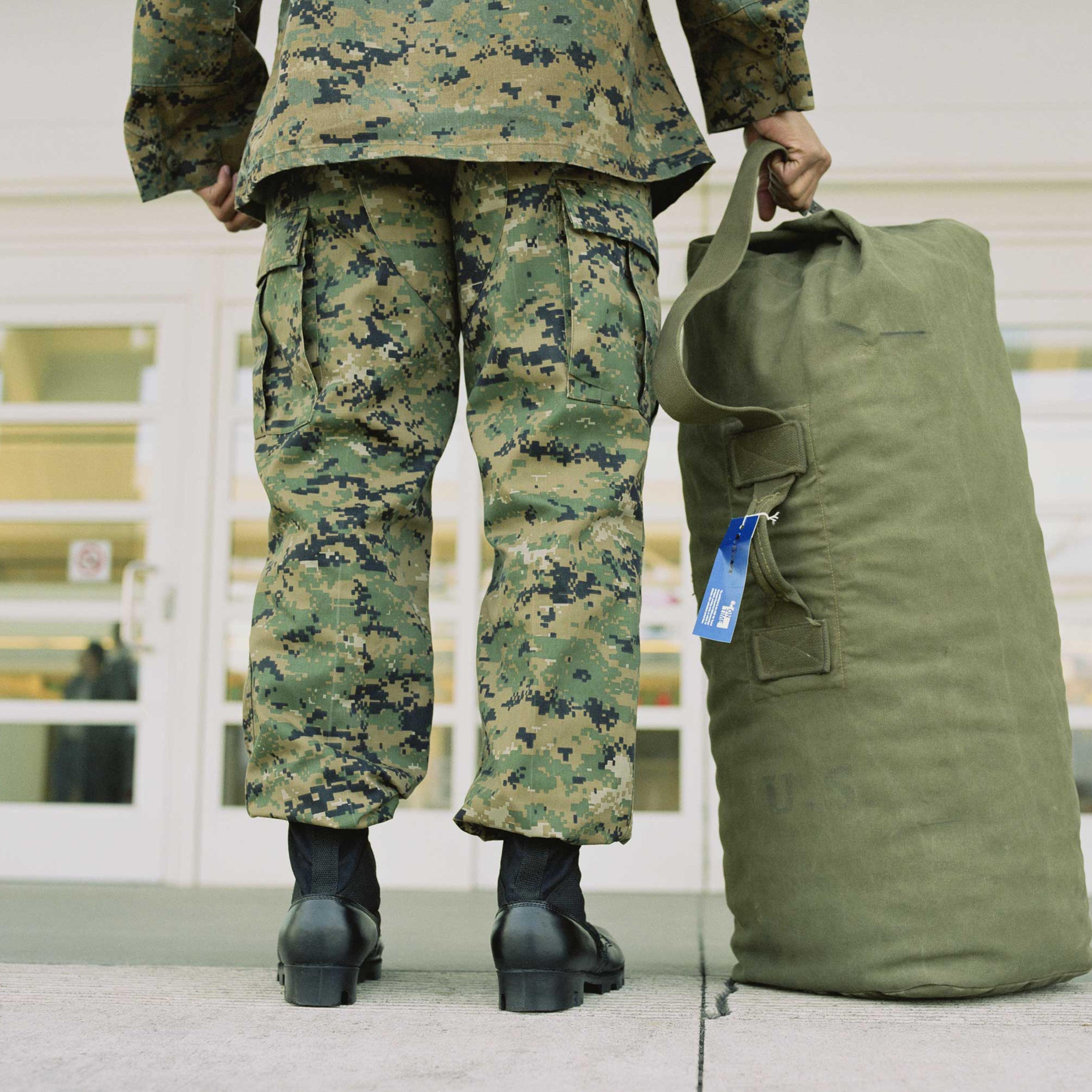 Military soldier with bag in airport, low section