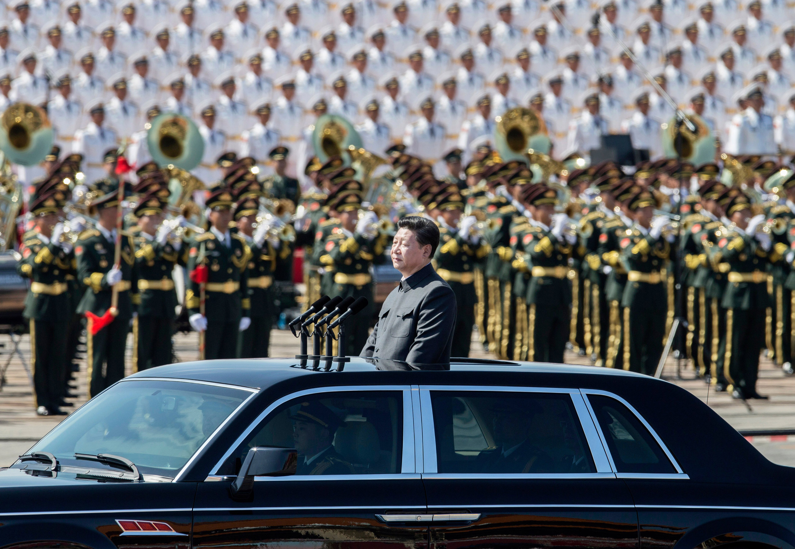 BEIJING, CHINA - SEPTEMBER 03: Chinese president and leader of the Communist Party Xi Jinping rides in an open top car in front of Tiananmen Square and the Forbidden City during a military parade on September 3, 2015 in Beijing, China. China is marking t