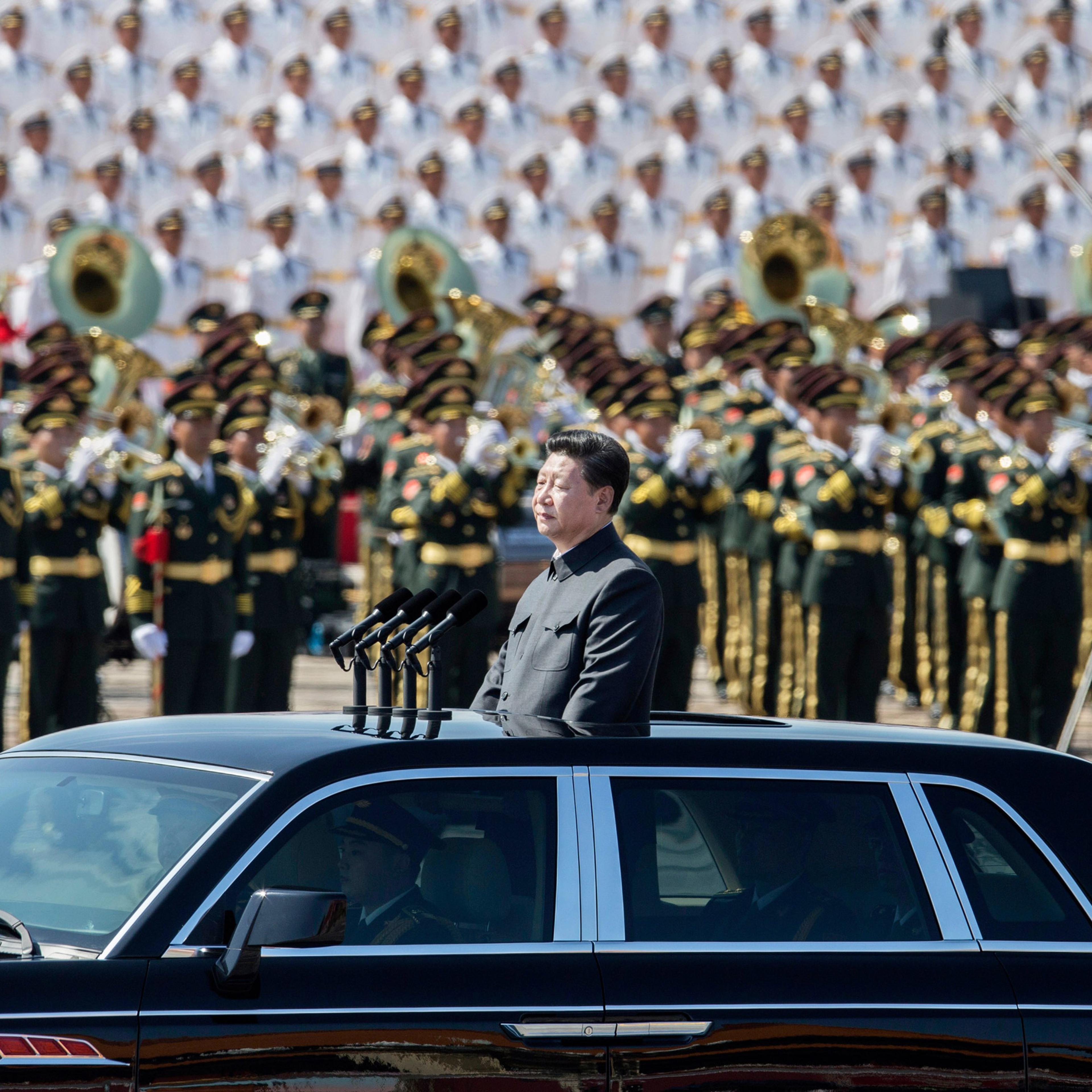 BEIJING, CHINA - SEPTEMBER 03: Chinese president and leader of the Communist Party Xi Jinping rides in an open top car in front of Tiananmen Square and the Forbidden City during a military parade on September 3, 2015 in Beijing, China. China is marking t