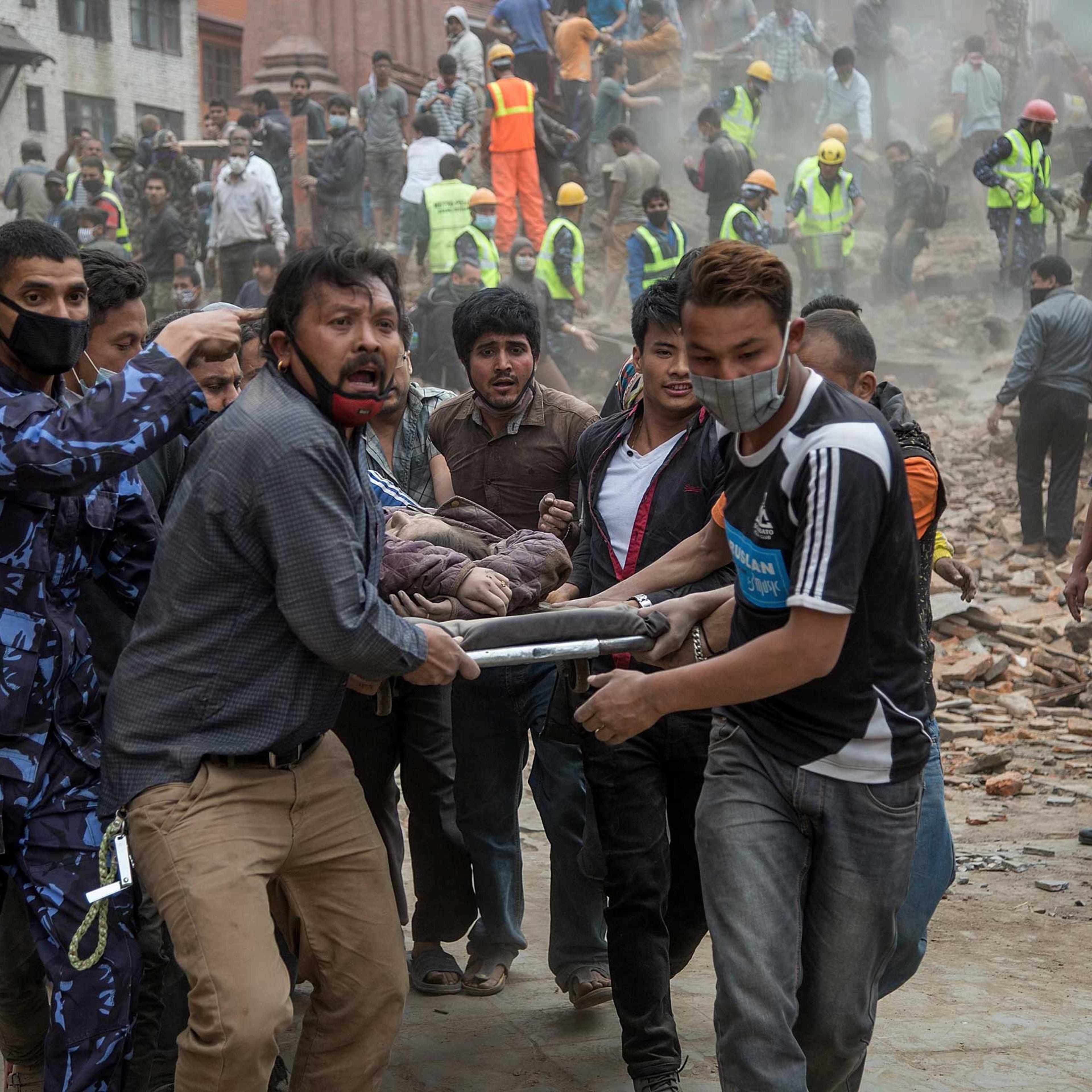 Emergency rescue workers carry a victim on a stretcher after Dharara tower collapsed in Kathmandu, Nepal on April 25, 2015