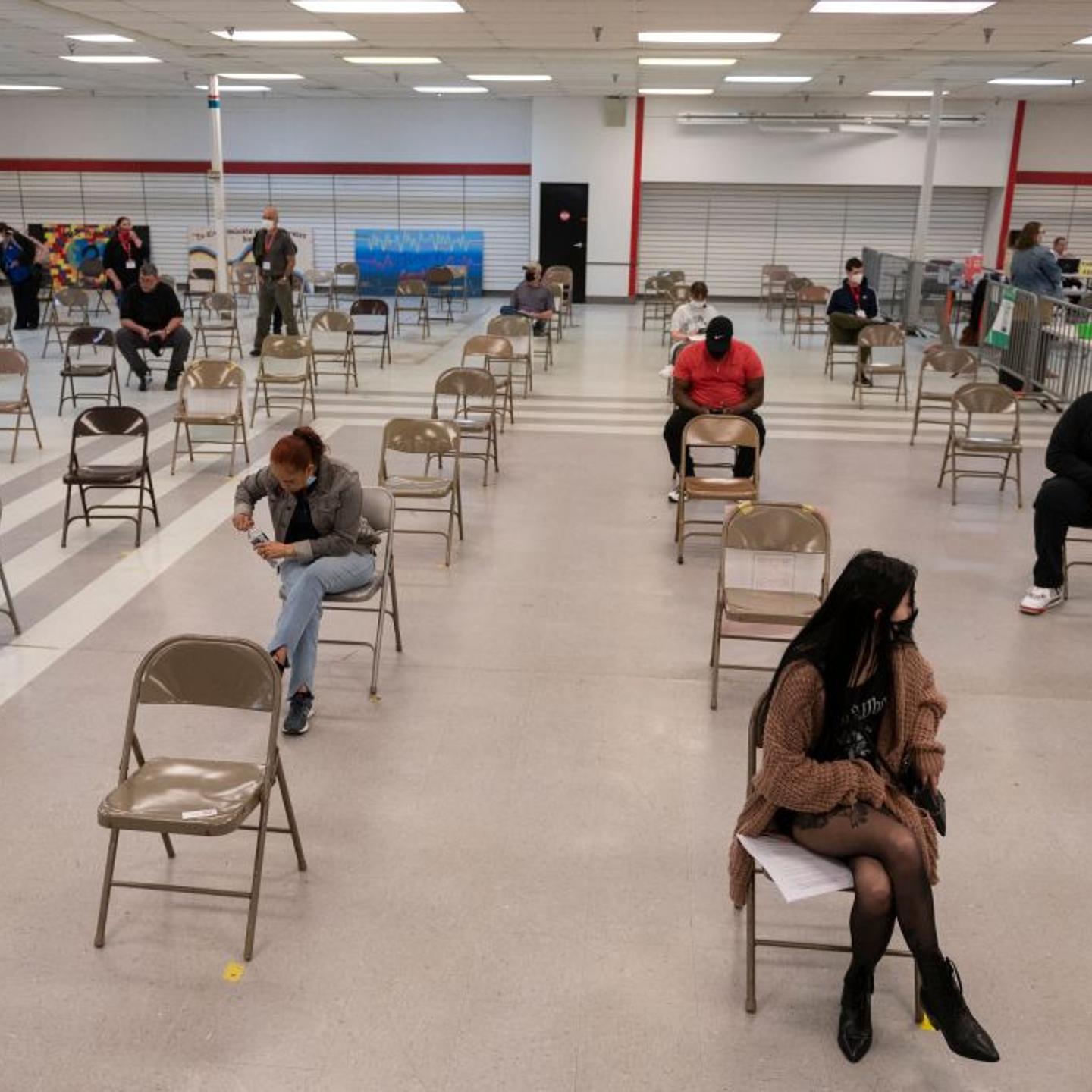 People wait in a observation area after getting a Covid-19 vaccination at an old TJ Maxx store used by Lynchburg Fire Department as a mass Covid-19 vaccination site in Lynchburg, Virginia on March 13