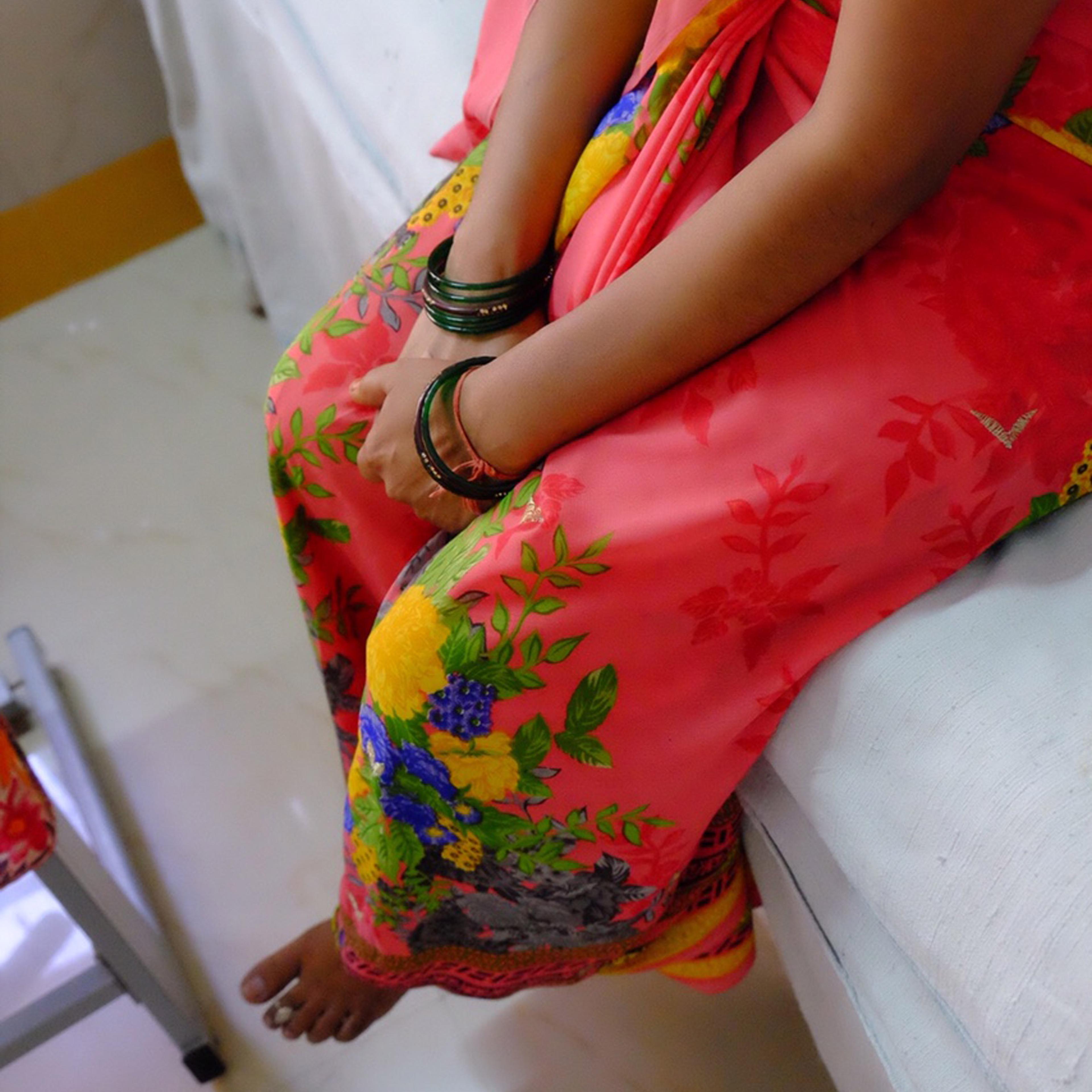 A woman sitting on a bed at an Udaipur hospital, waiting for an IUD insertion.