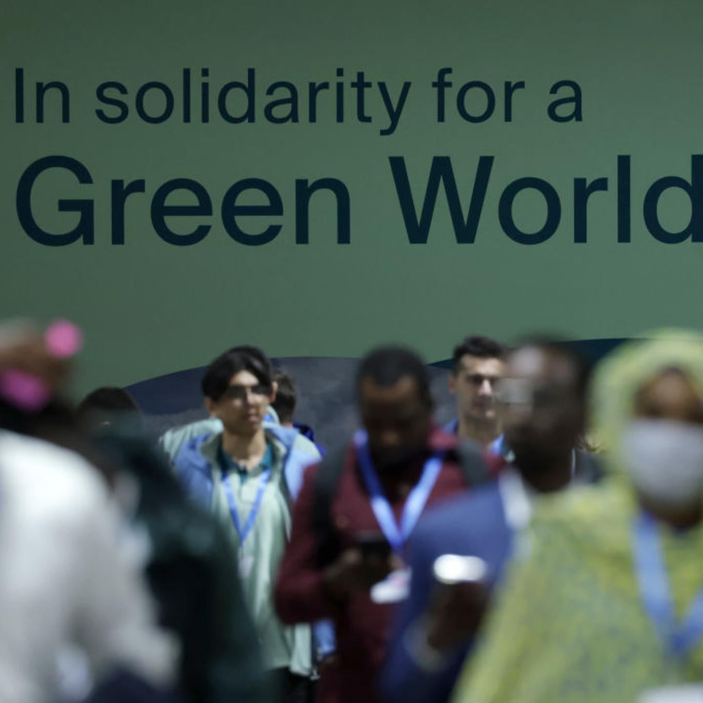 COP29 participants walk past a banner that reads: "In solidarity with a Green World" on the opening day of the Climate Conference on Nov. 11, 2024 in Baku, Azerbaijan.