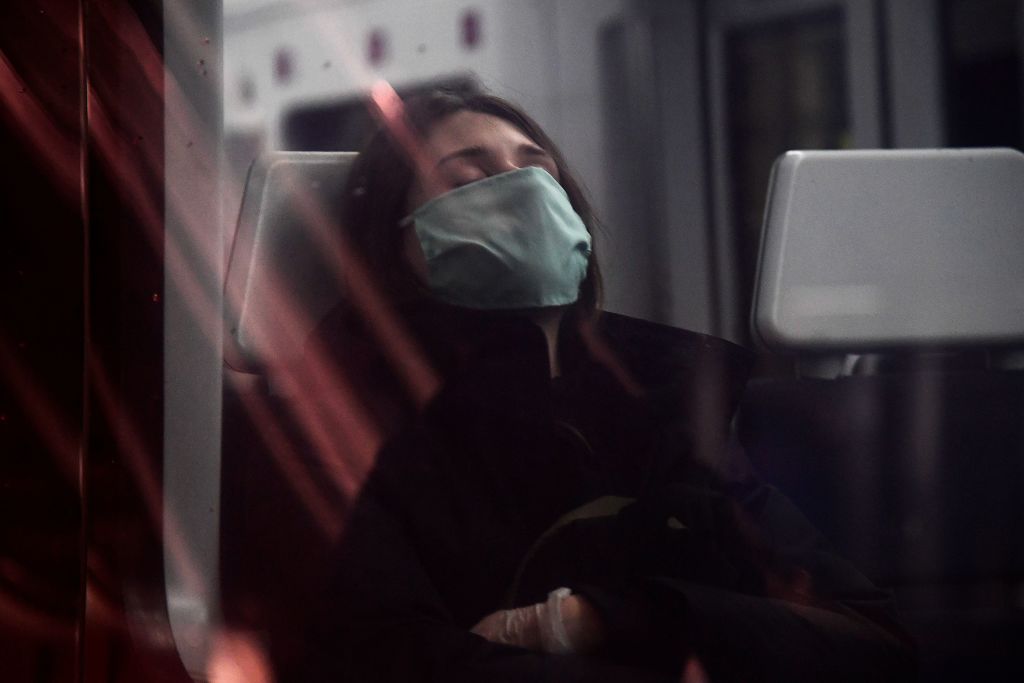 A woman wearing a face mask sleeps on a train at the Atocha Station in Madrid on April 13, 2020.
