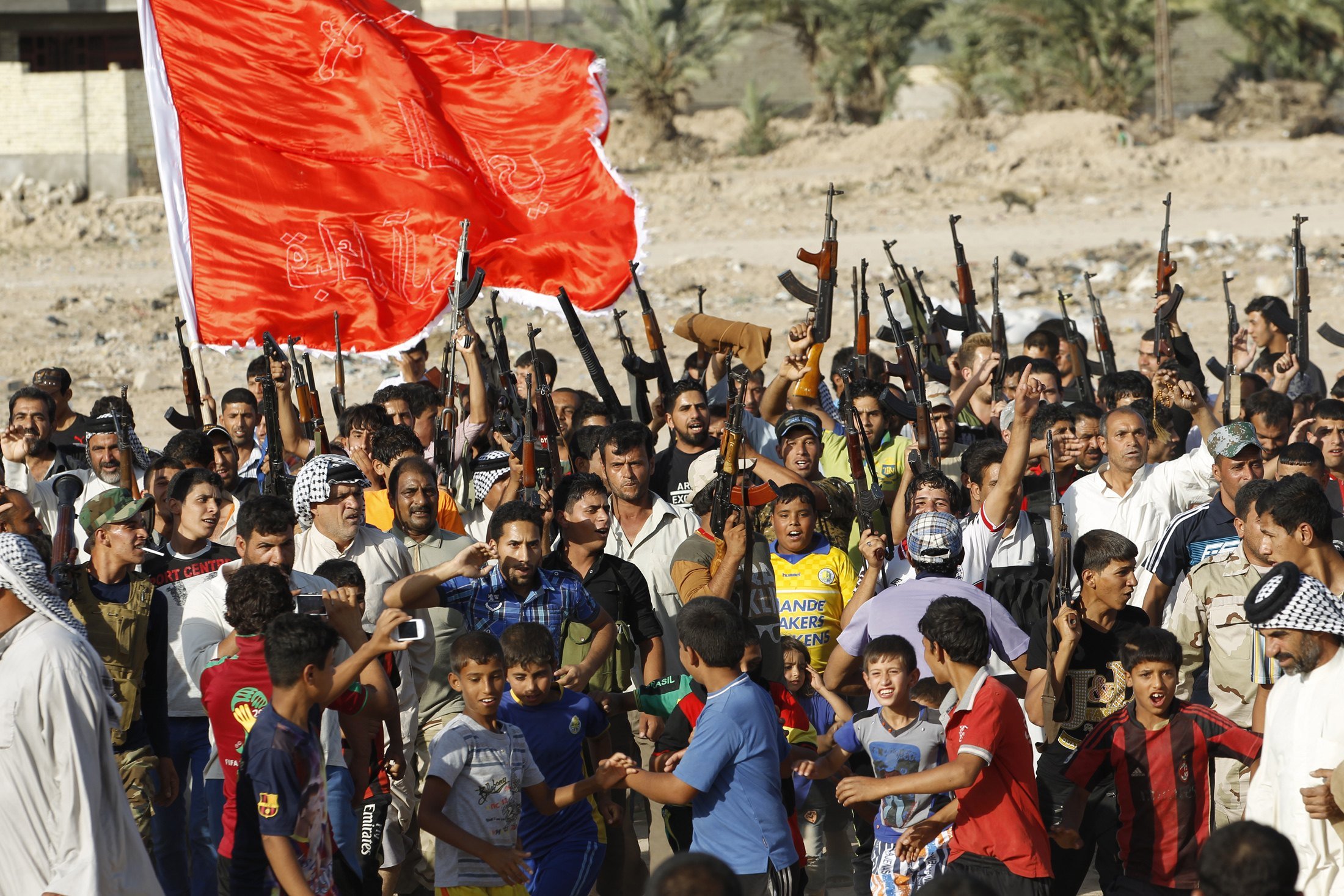 Volunteers, who have joined the Iraqi Army to fight against predominantly Sunni militants from the radical Islamic State of Iraq and the Levant, carry weapons during a parade in Al-Fdhiliya district