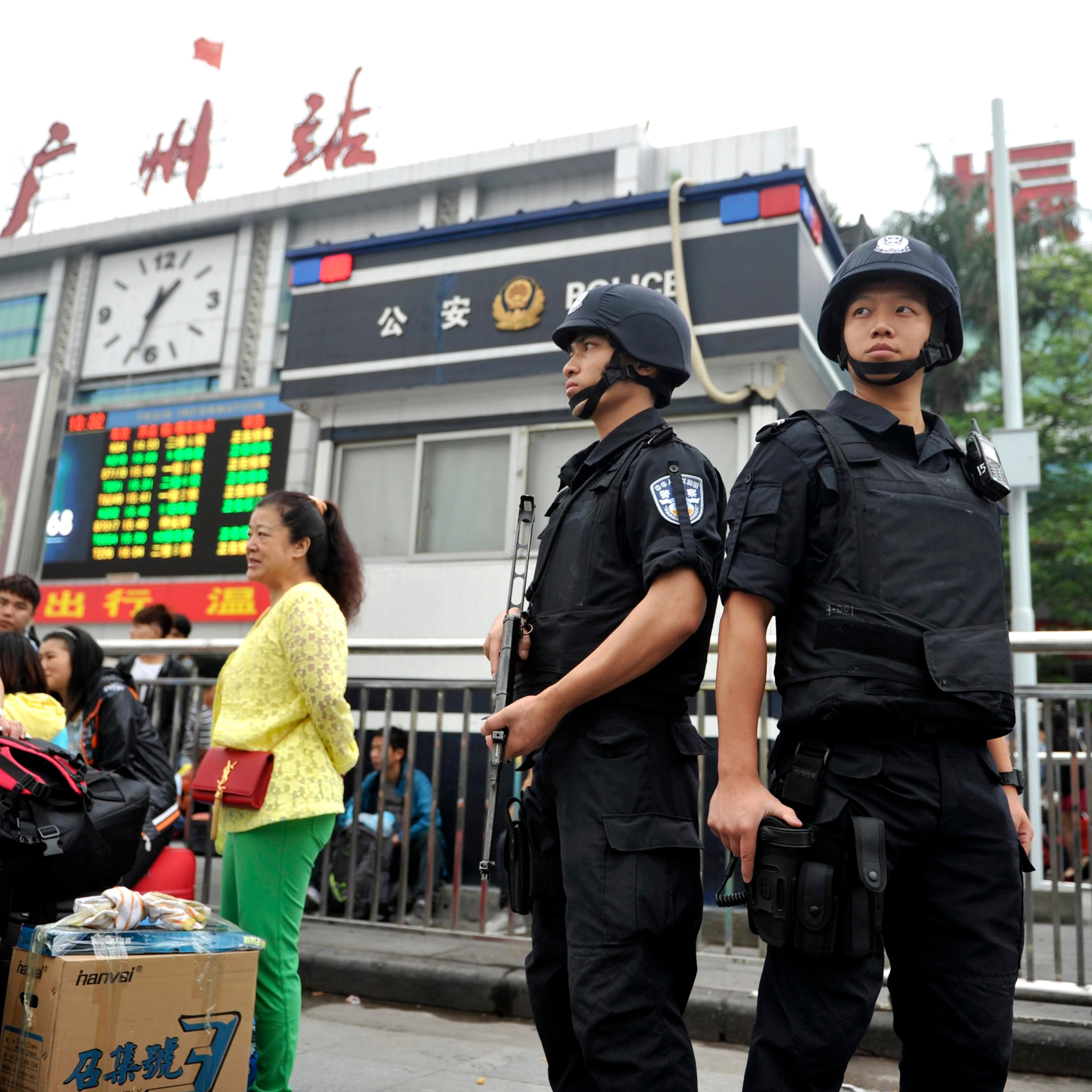 Armed policemen stand guard next to passengers after a knife attack at a railway station in Guangzhou, Guangdong province May 6, 2014.