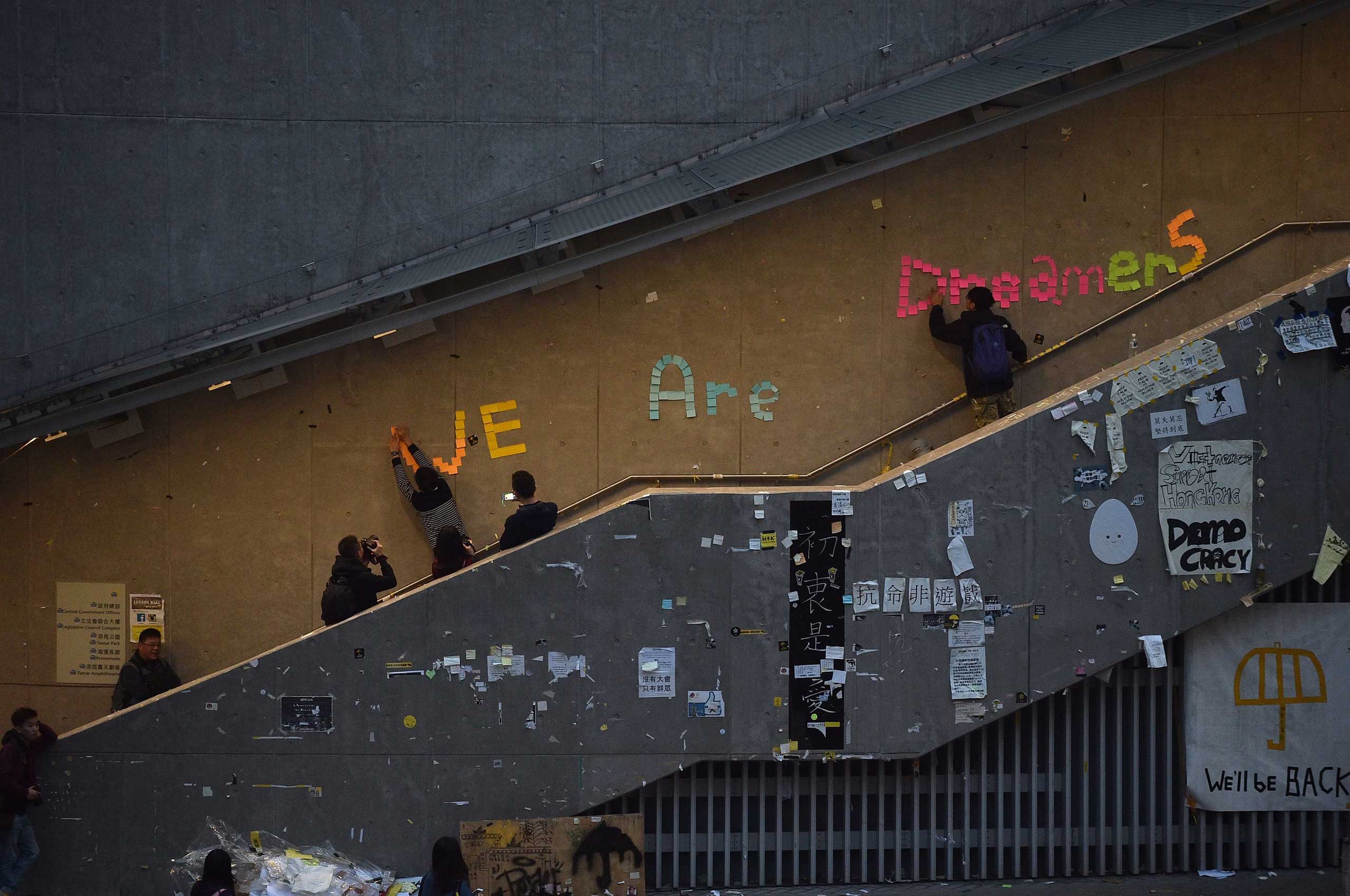 Pro-democracy protesters remove signs placed up during the past two months of protests from the area around the protest camp but leave intact the notice "We are dreamers" in the Admiralty in Hong Kong on Dec. 11, 2014.