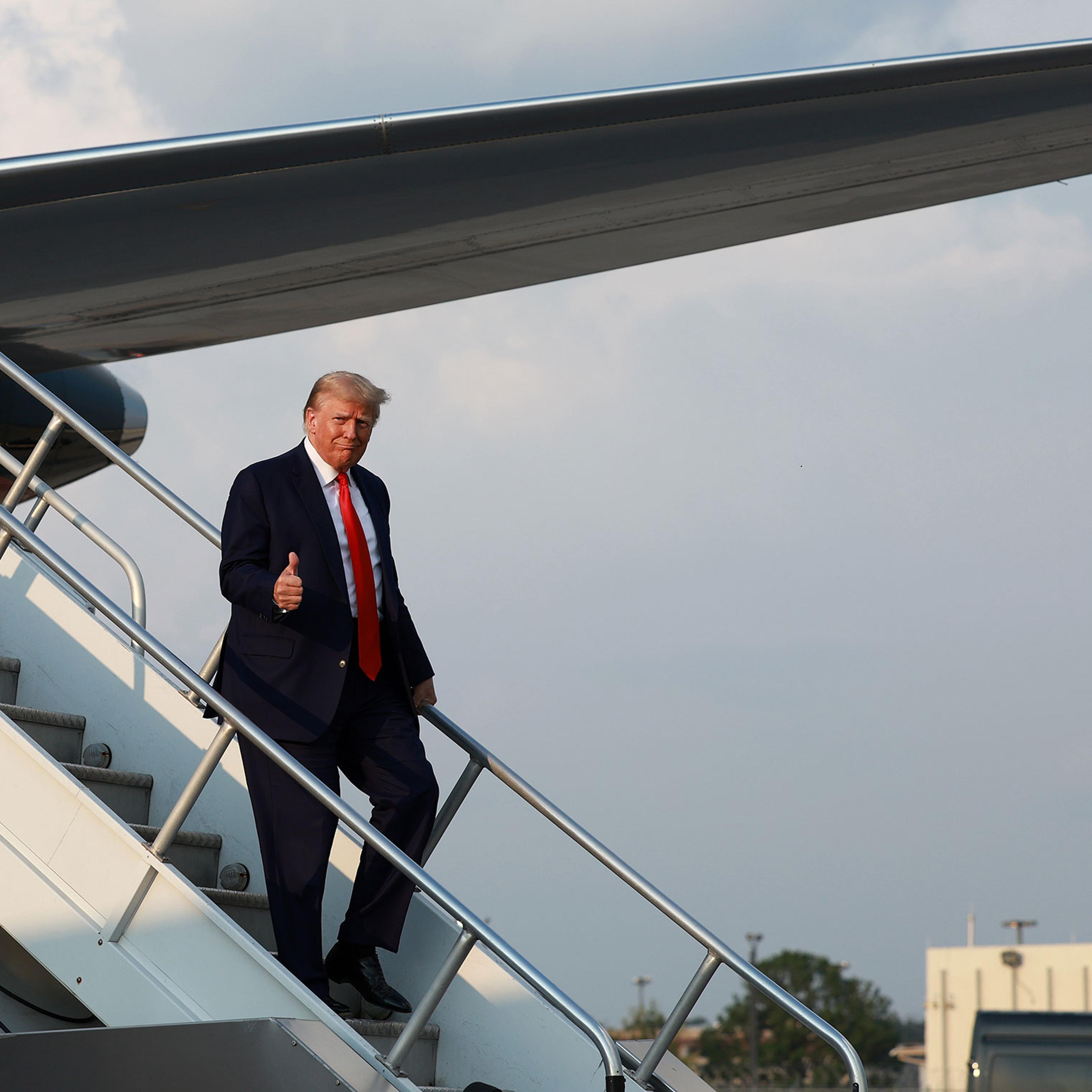Former President Donald Trump gives a thumbs up as he arrives at Atlanta Hartsfield-Jackson International Airport on in Atlanta, Aug. 24, 2023.