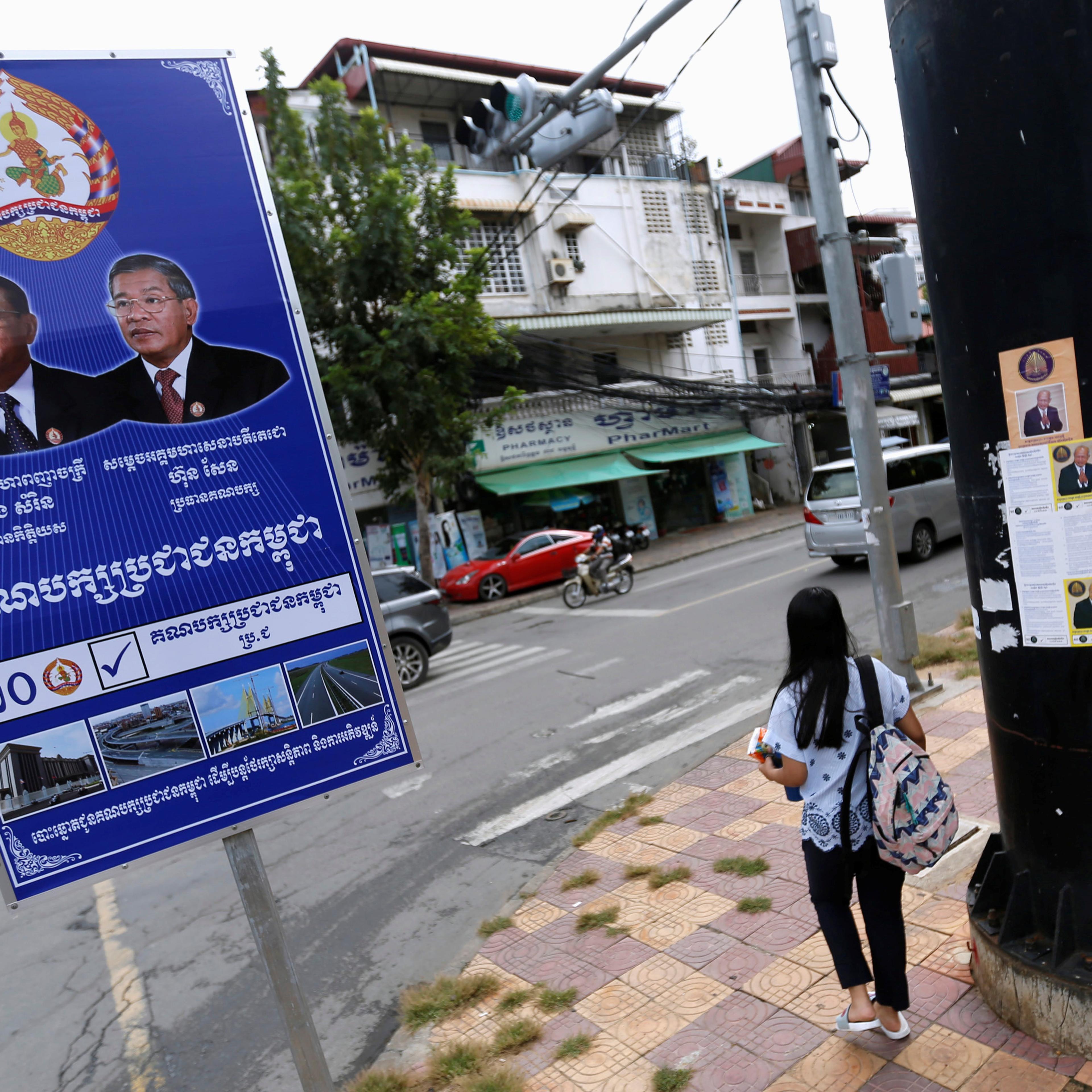 Posters of the Cambodian People's Party (CPP) and FUNCINPEC Party are seen along a street in Phnom Penh