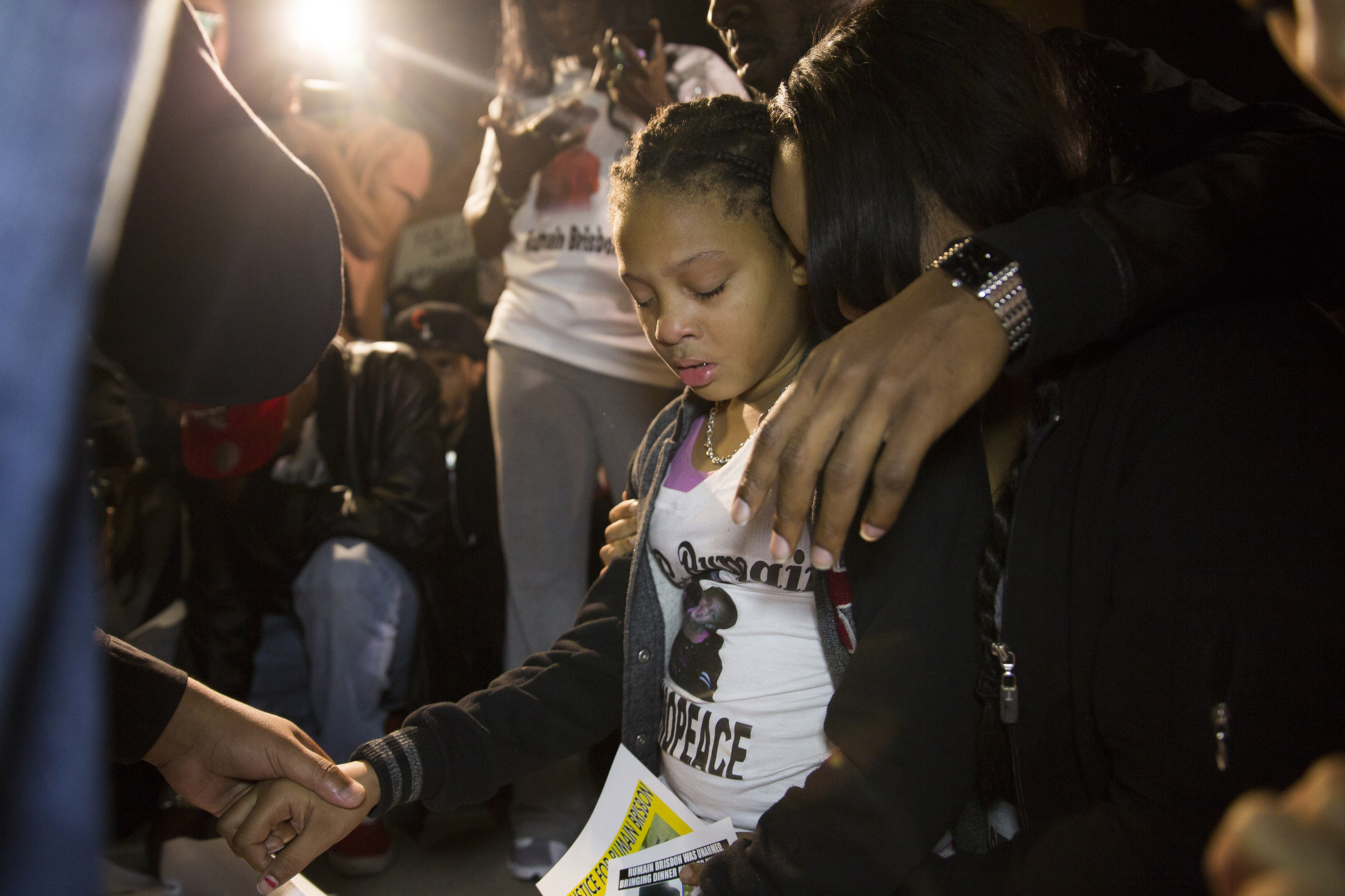 The daughter of Rumain Brisbon (L) begins crying as she kneels in prayer at a vigil for her father who was fatally shot by police, in Phoenix, Ariz. on Dec. 8, 2014.