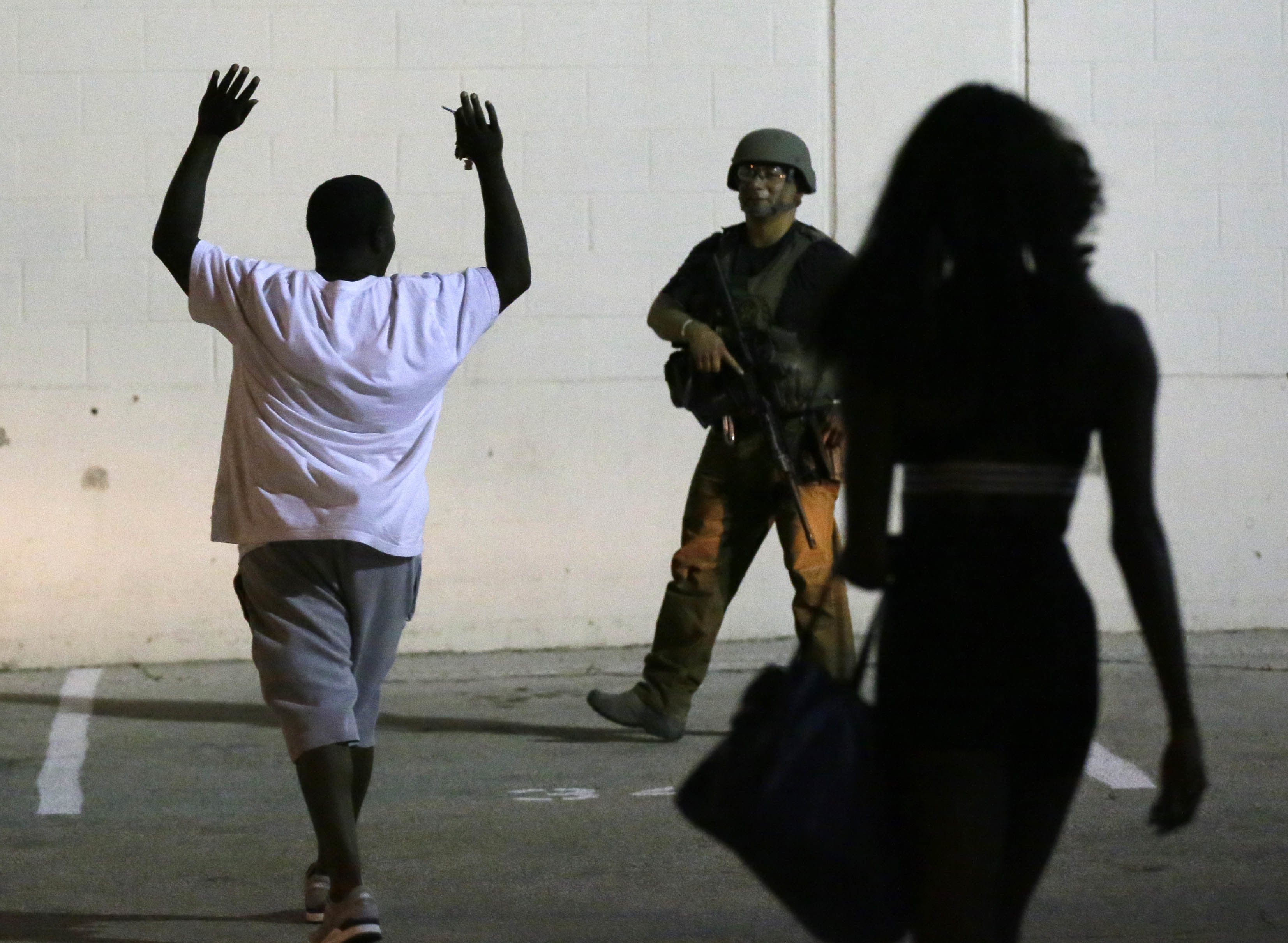 A man raises his hands as he walks near a law enforcement officer, following the shootings Thursday of several police officers in downtown Dallas, early Friday, July 8, 2016.