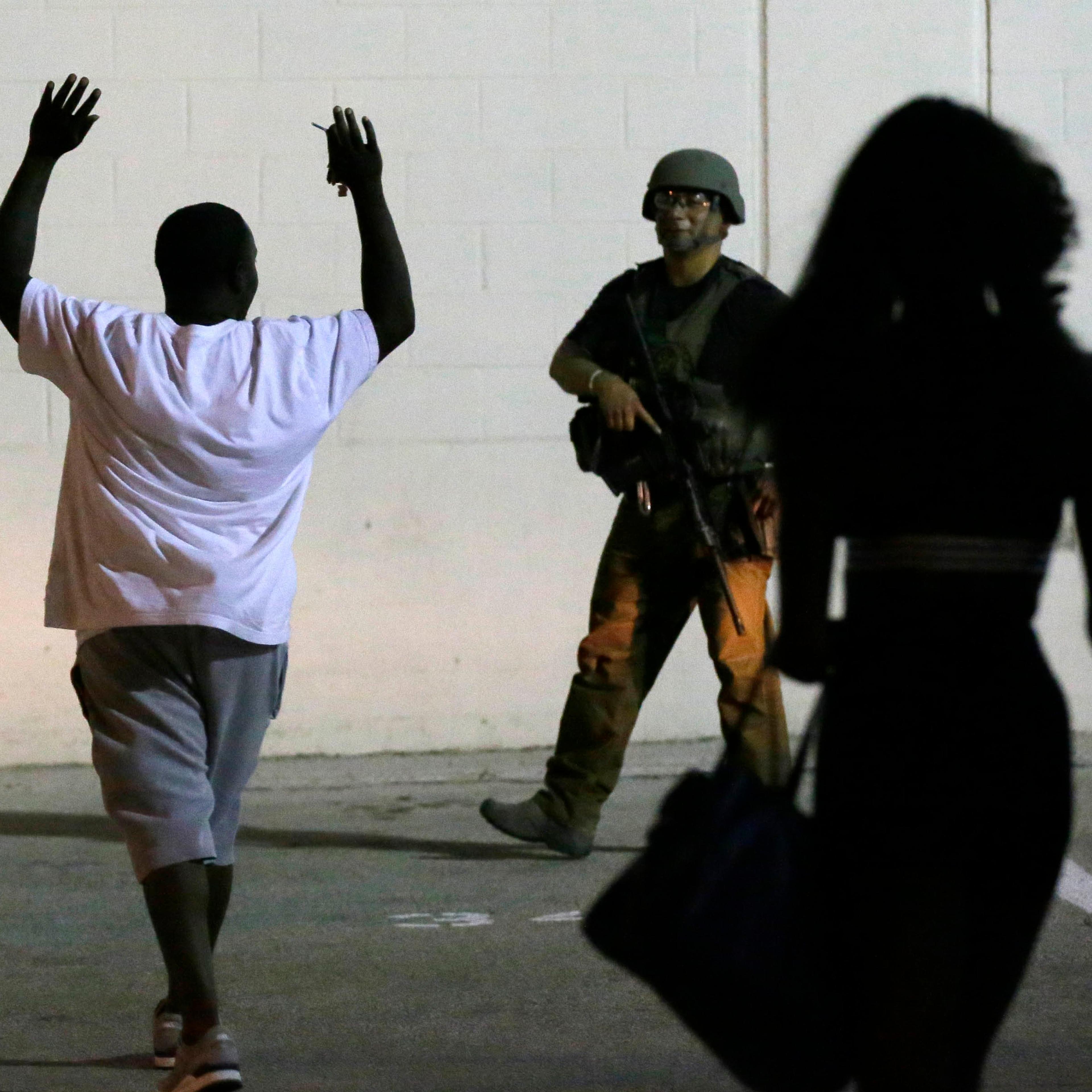 A man raises his hands as he walks near a law enforcement officer, following the shootings Thursday of several police officers in downtown Dallas, early Friday, July 8, 2016.