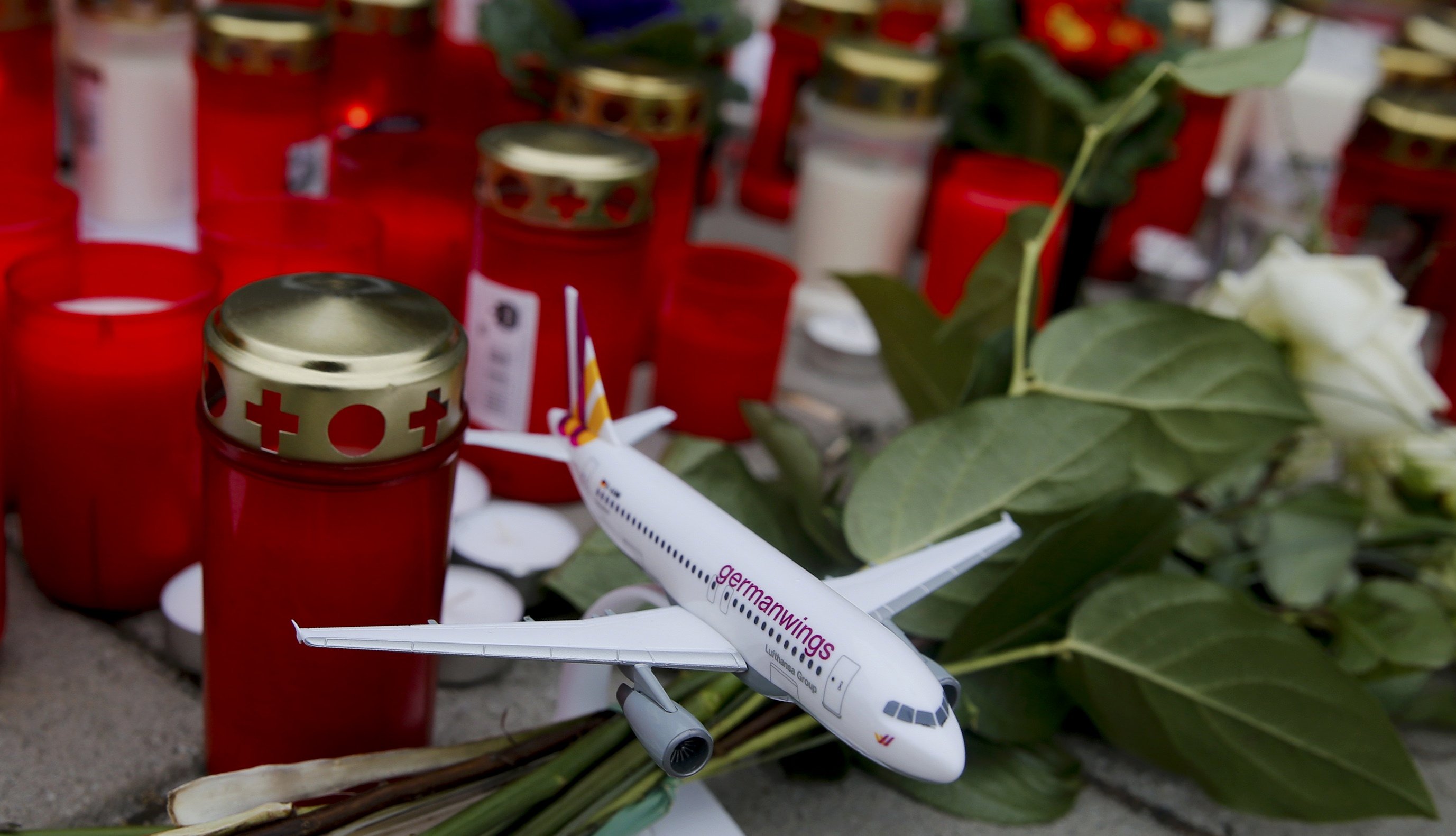 A model of a Germanwings plane is placed among flowers and lit candles in Cologne Bonn airport, March 26, 2015.