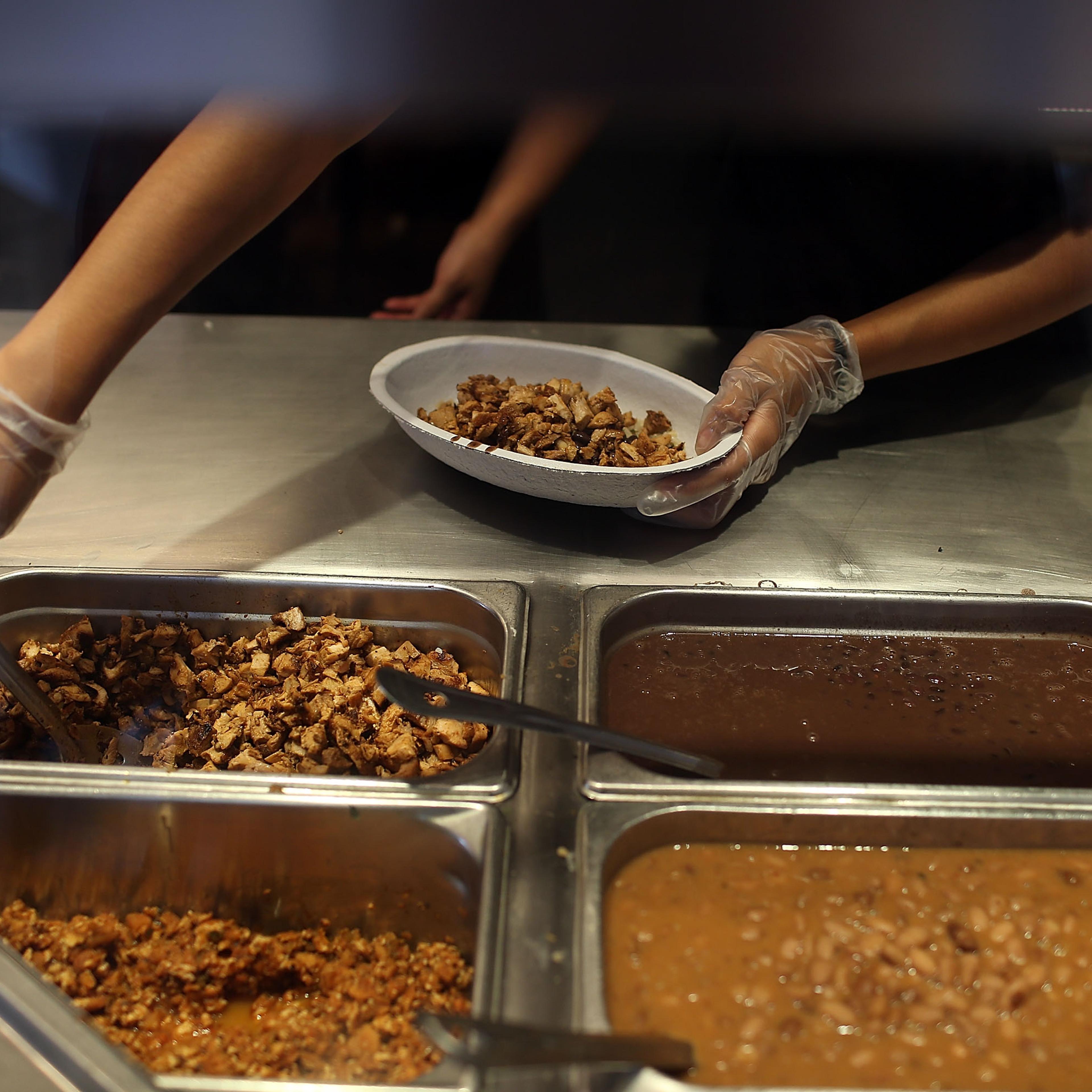 Chipotle restaurant workers fill orders for customers on the day that the company announced it will only use non-GMO ingredients in its food on April 27, 2015 in Miami, Florida.