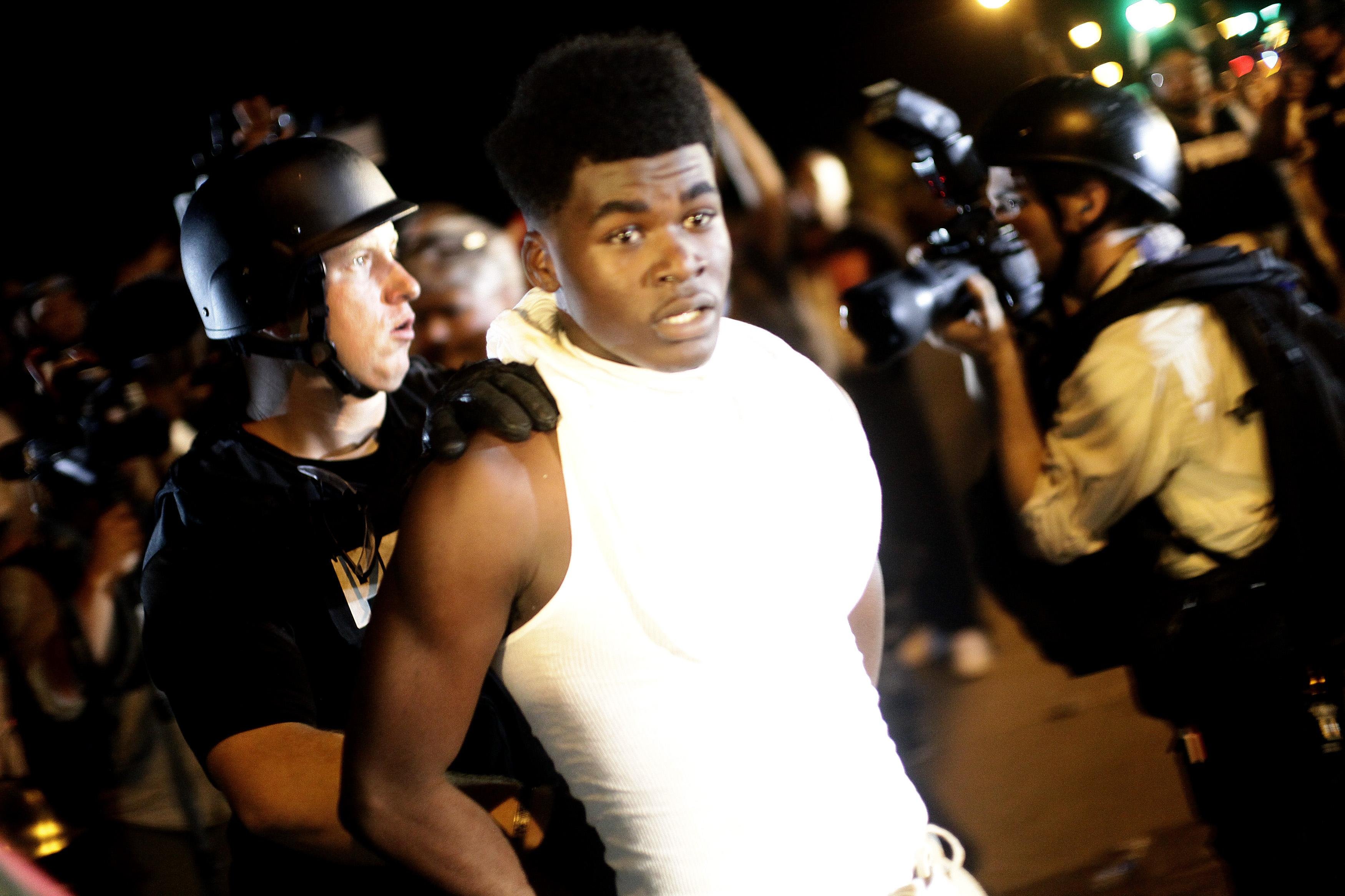 A police officer in riot gear detains a demonstrator protesting against the shooting of Michael Brown, in Ferguson