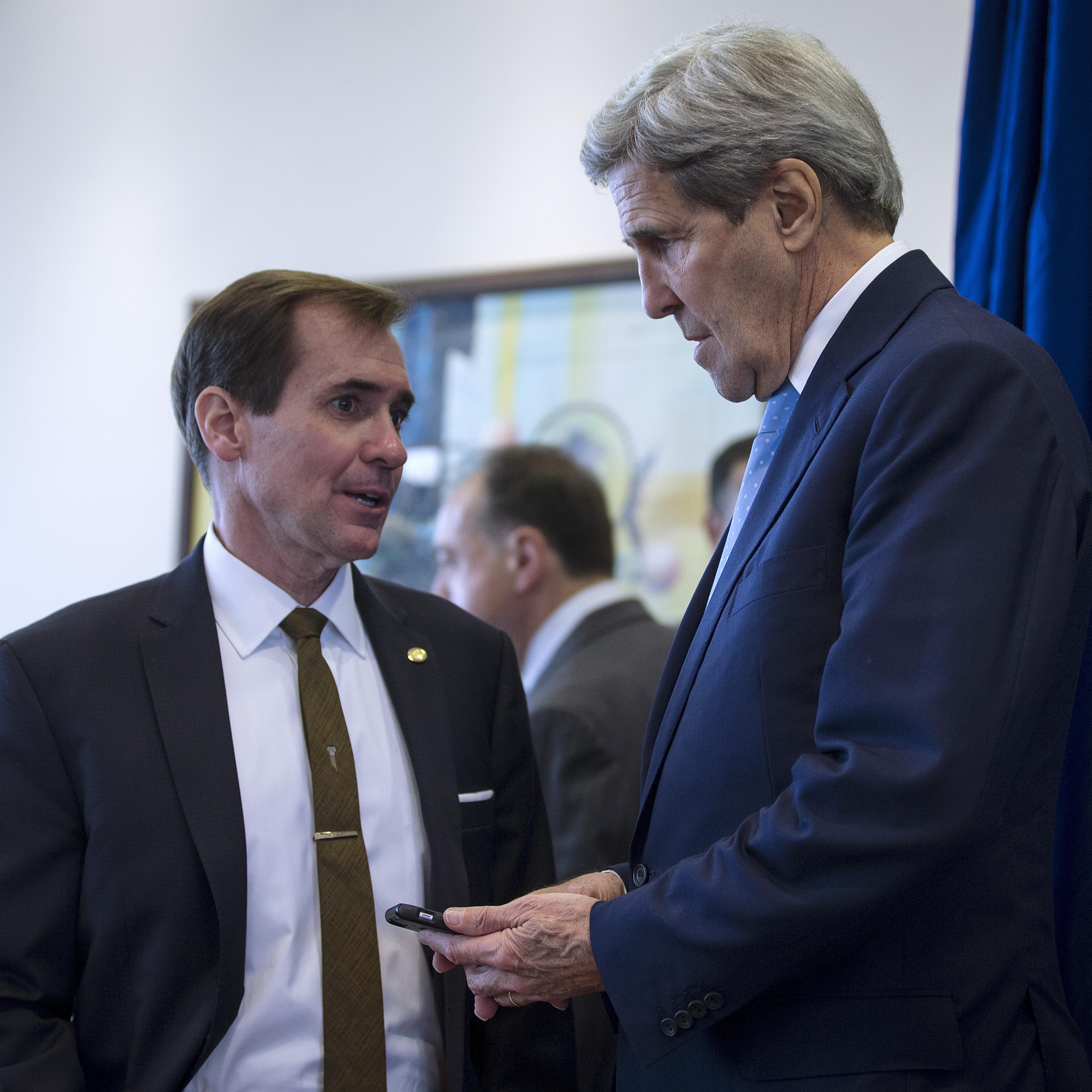 U.S. Secretary of State John Kerry speaks to senior advisor John Kirby before he holds a briefing at Amman Civil Airport in Amman