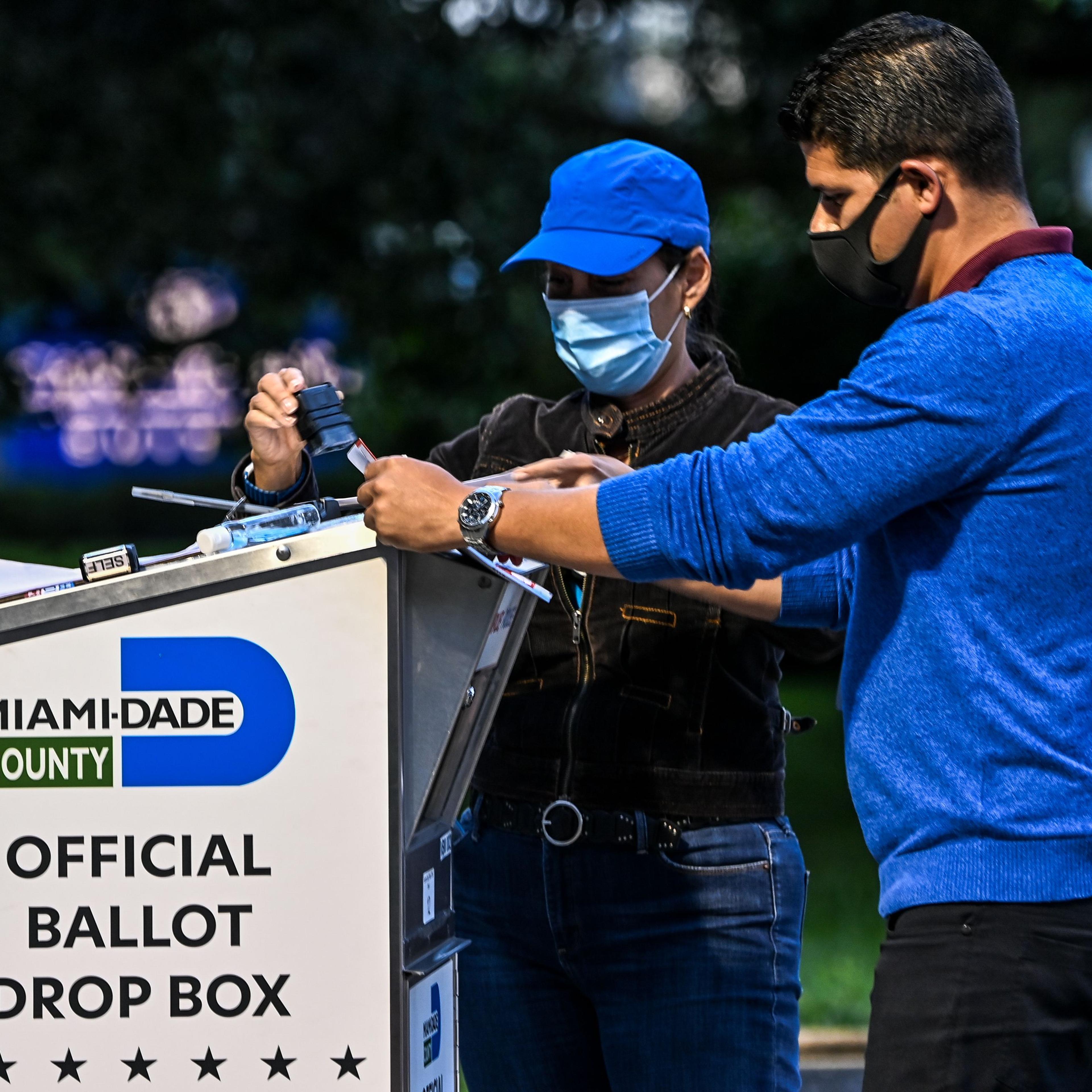 A poll worker helps a voter put as she drops off her mail-in ballot at an official Miami-Dade County drive-thru ballot drop box at the Miami-Dade County Election Department in Miami, on Nov. 3, 2020.