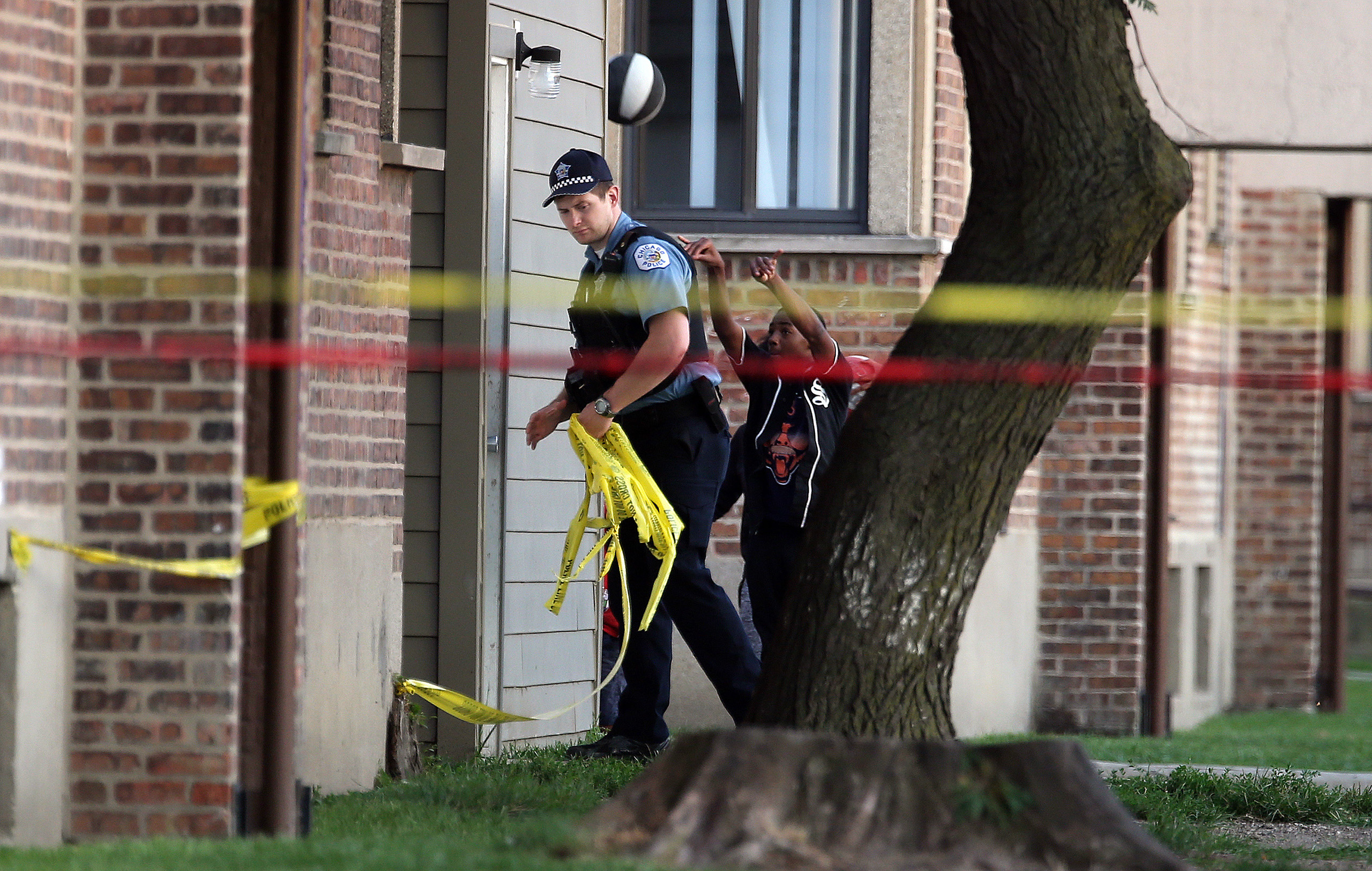 Kids play basketball as Chicago Police remove crime scene tape after a fatal shooting on Calumet Avenue south of 63rd Street on Aug. 26, 2016.