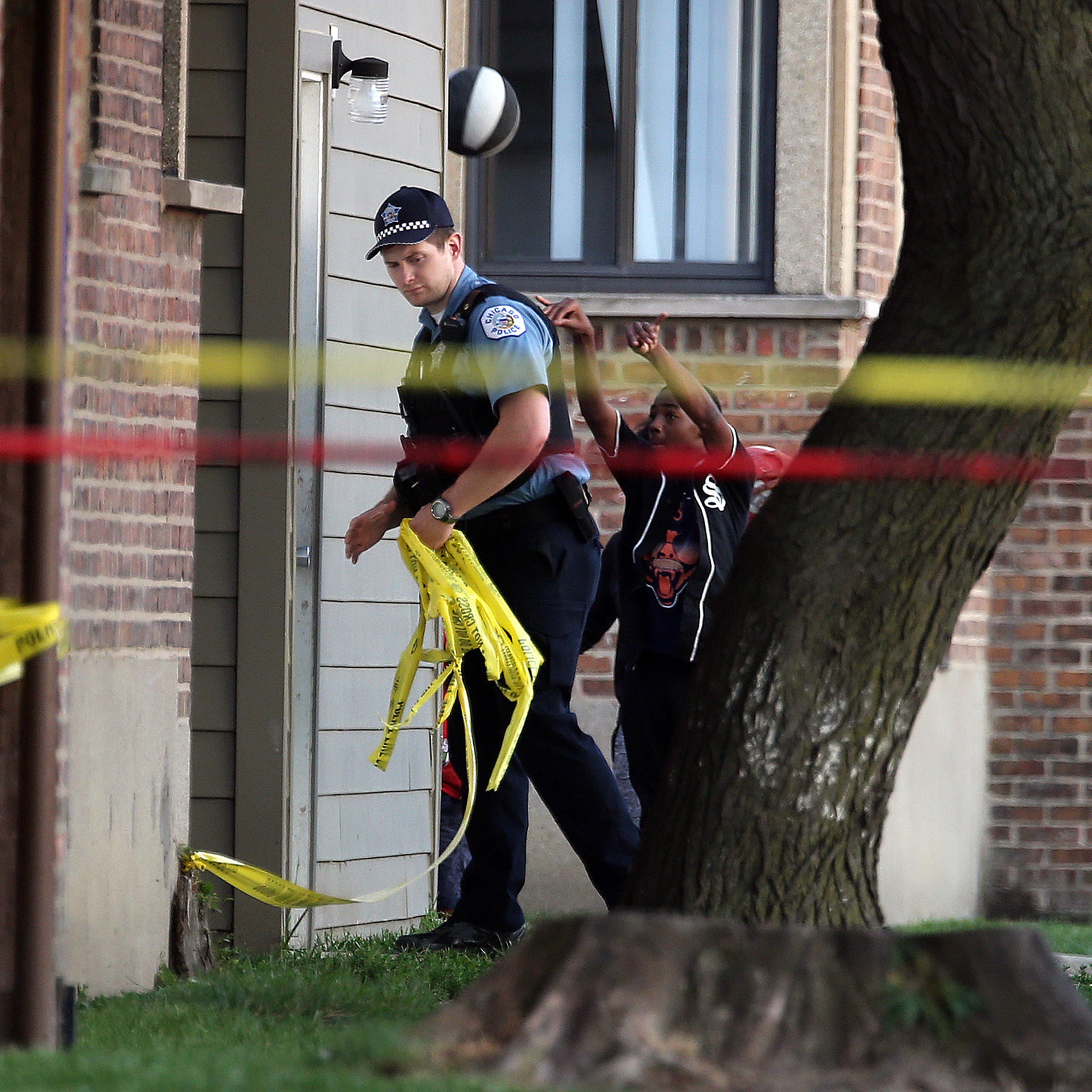 Kids play basketball as Chicago Police remove crime scene tape after a fatal shooting on Calumet Avenue south of 63rd Street on Aug. 26, 2016.
