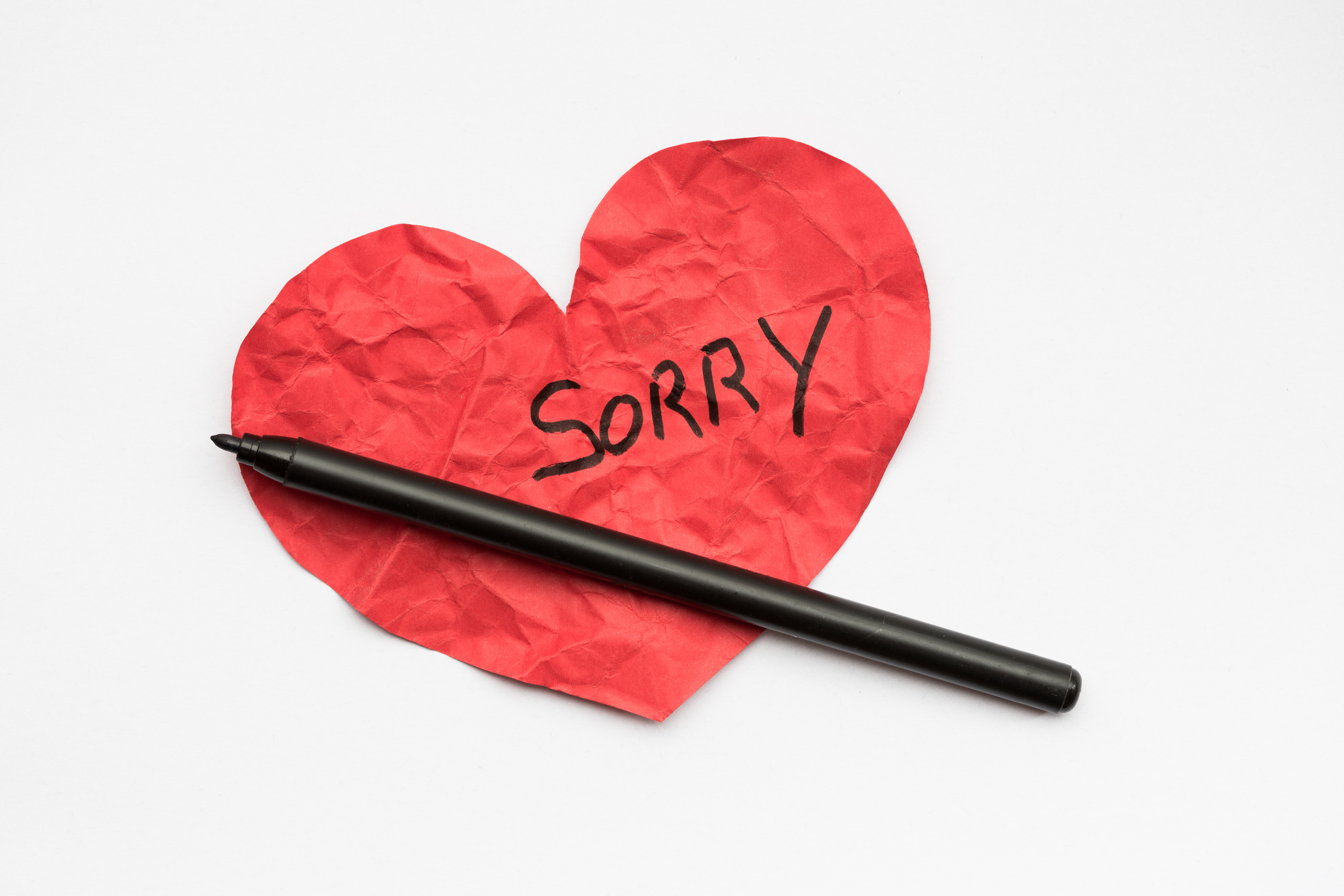 Crumpled red paper heart with pen