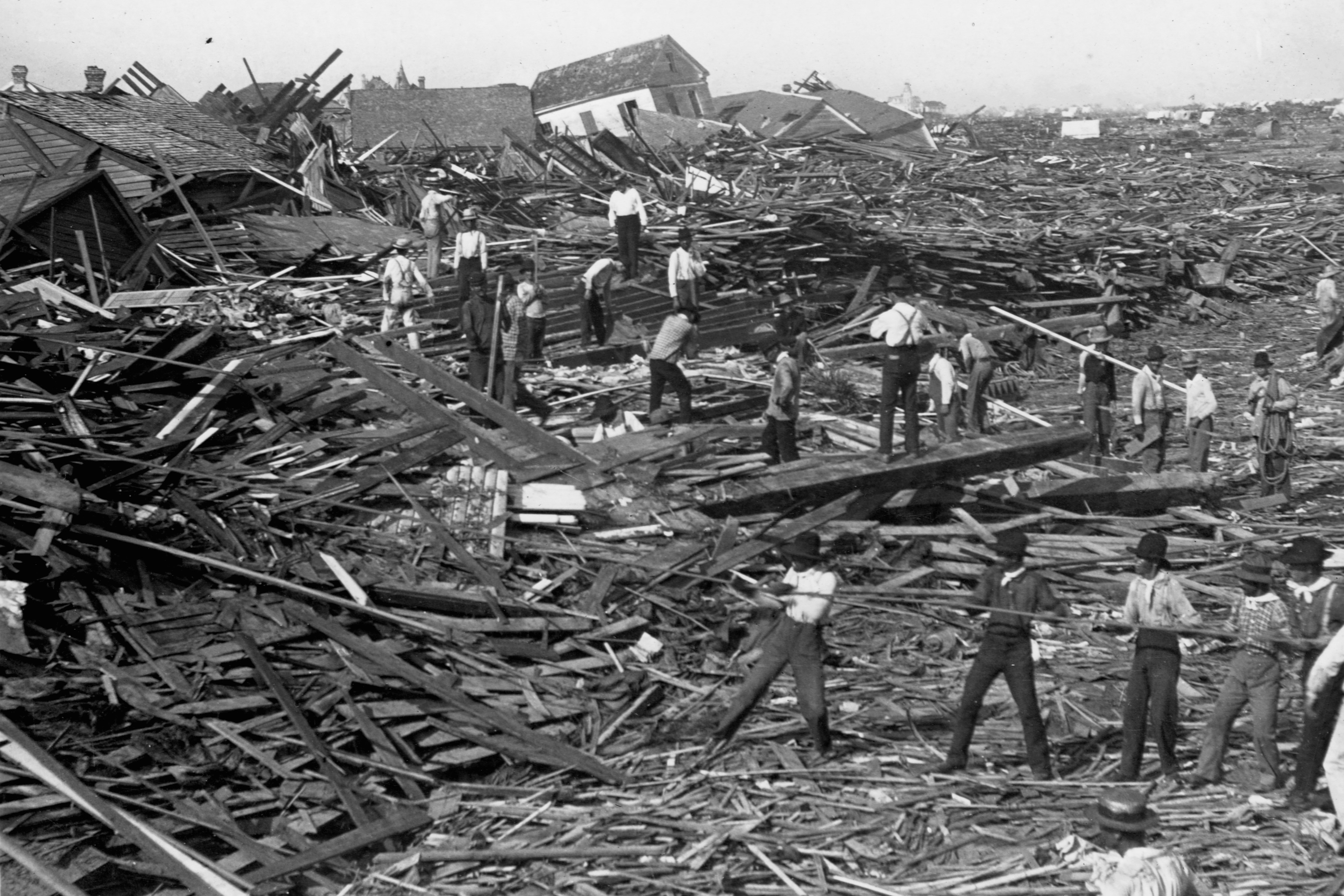 Men use ropes to pull away the debris of houses in order to look for bodies, after the Galveston Hurricane of 1900. 