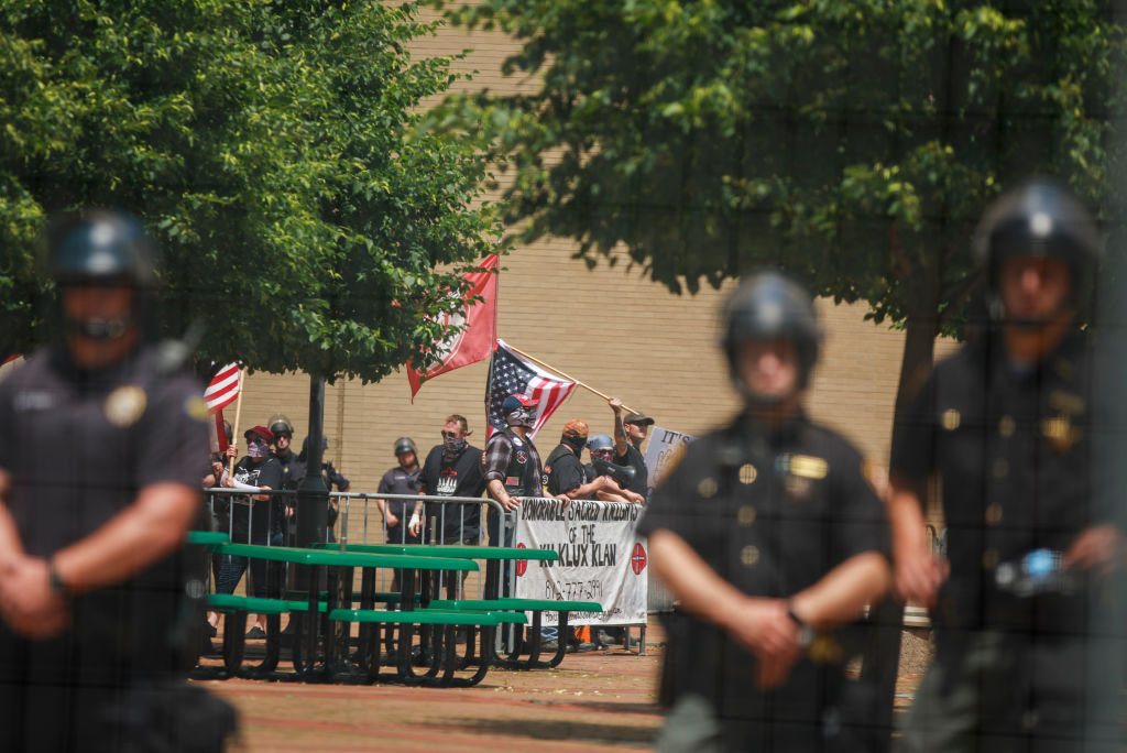 Police guard members of the KKK who are holding a rally.