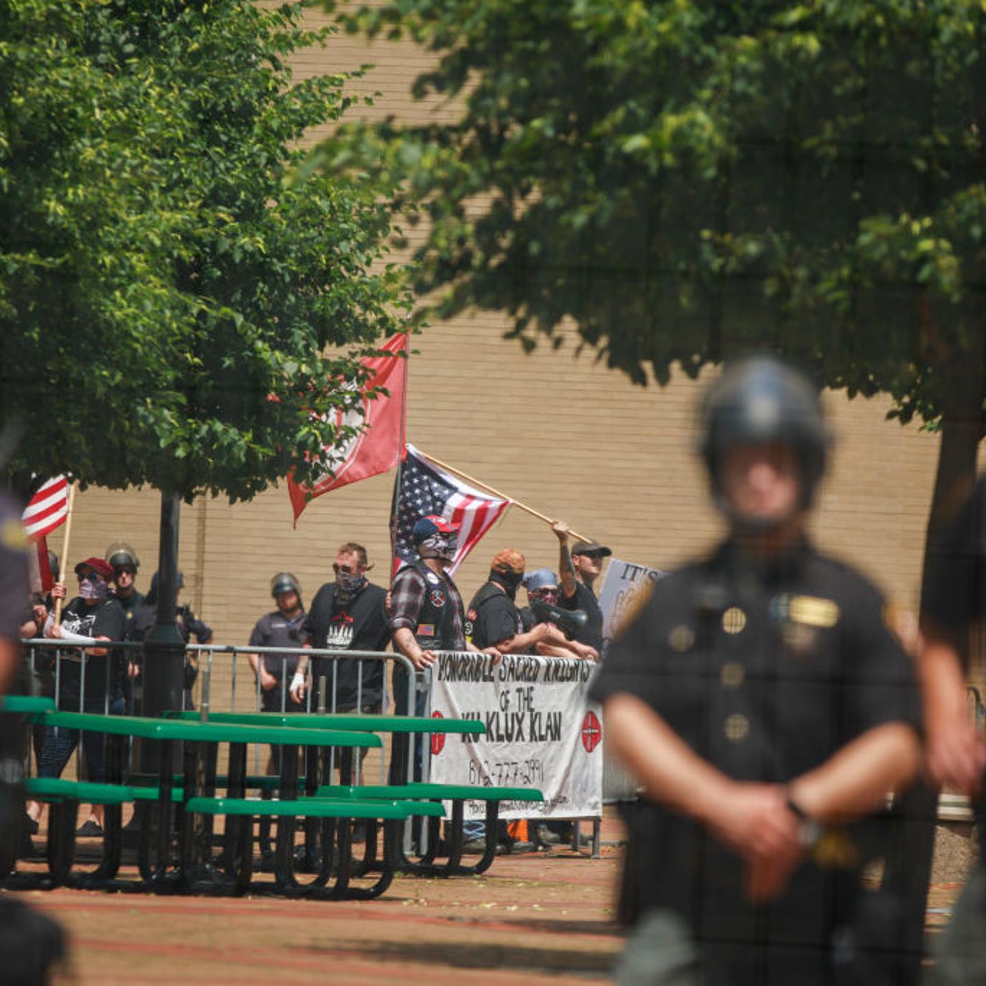 Police guard members of the KKK who are holding a rally.