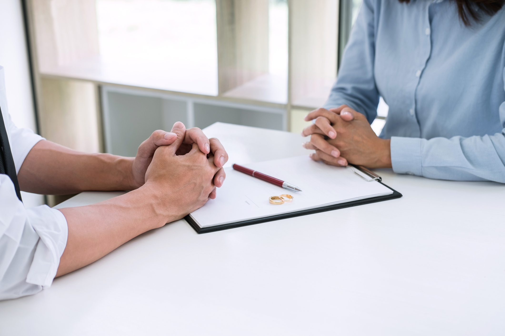 Midsection Of Couple With Divorce Paper And Wedding Rings On Table