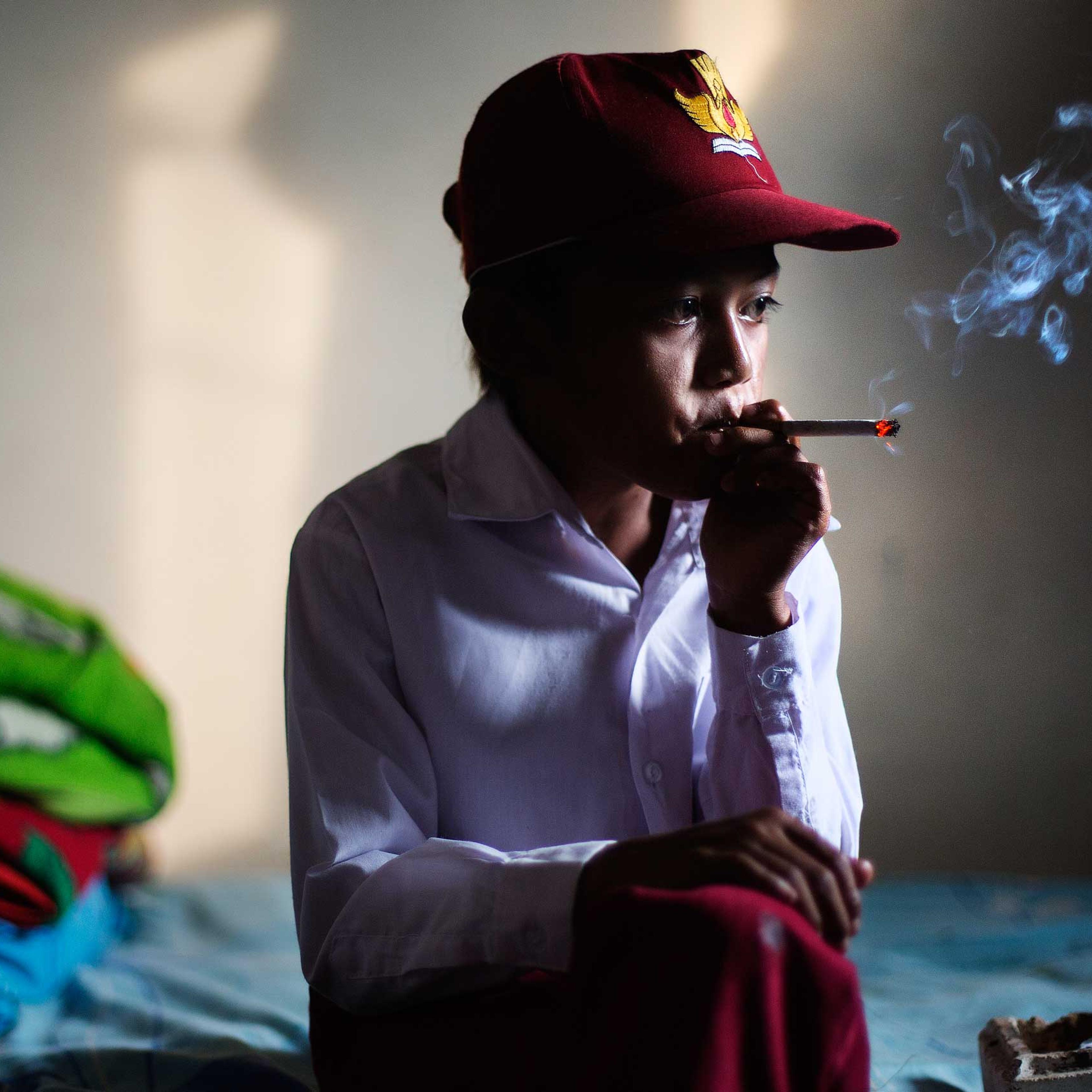 Ilham Hadi, who has smoked up to two packs a day and began when he was four years old, poses for a photo wearing his third grade uniform while smoking in his bedroom in a village near the town of Sukabumi, Indonesia on February 14, 2014.