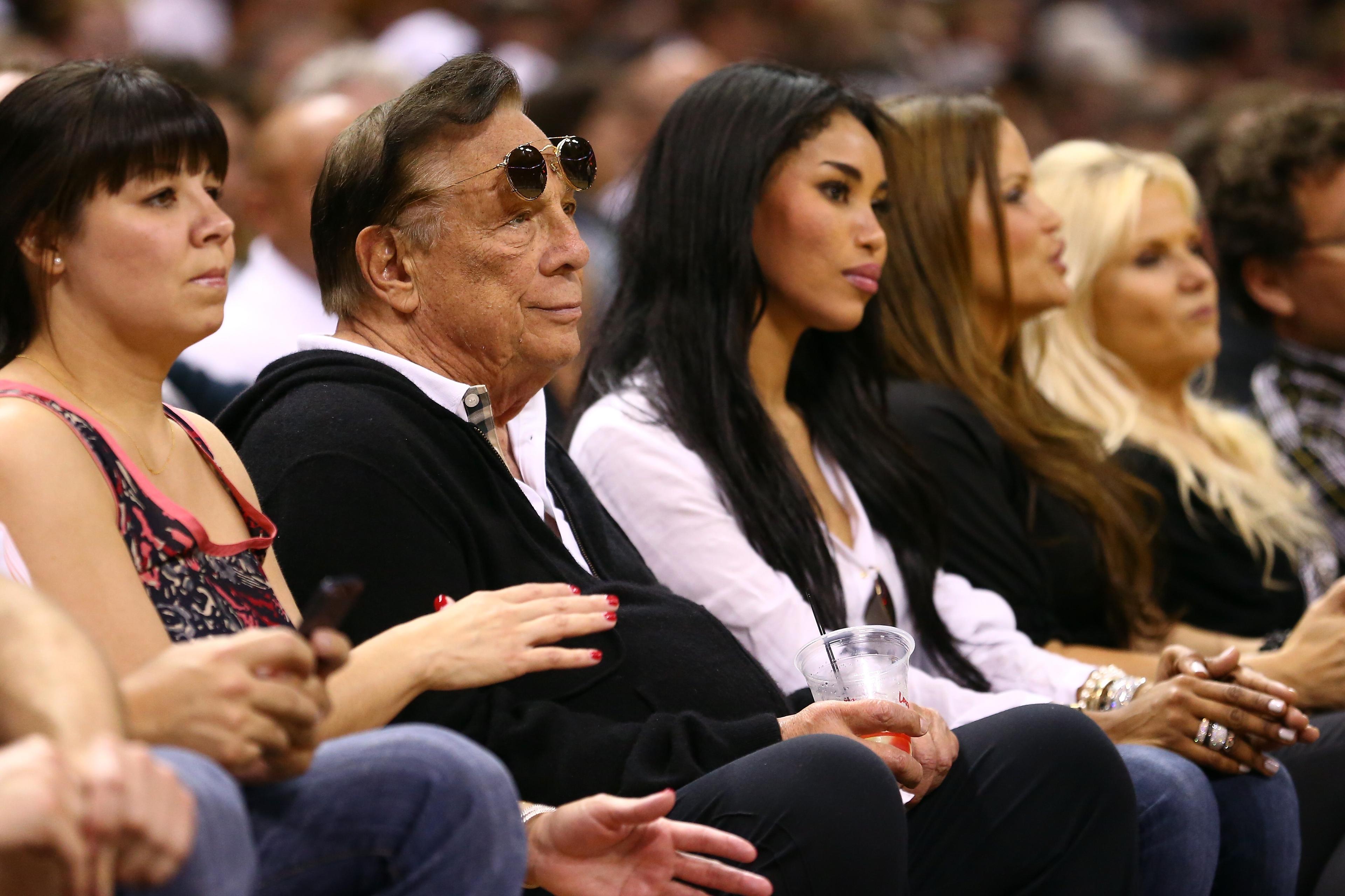 Team owner Donald Sterling (center) of the Los Angeles Clippers and V. Stiviano (second from right) watch the San Antonio Spurs play against the Memphis Grizzlies in San Antonio on May 19, 2013.
