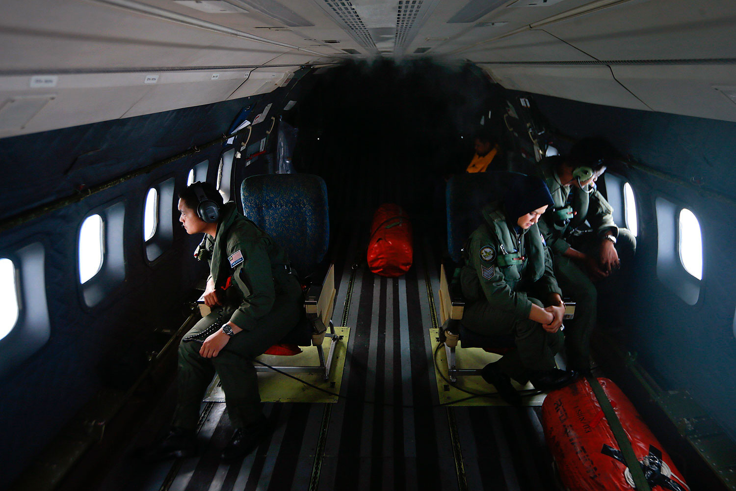 Crew members from the Royal Malaysian Air Force look through windows of a Malaysian Air Force CN235 aircraft during a Search and Rescue operation to find the missing Malaysia Airlines flight MH370, in the Straits of Malacca, March 13, 2014.