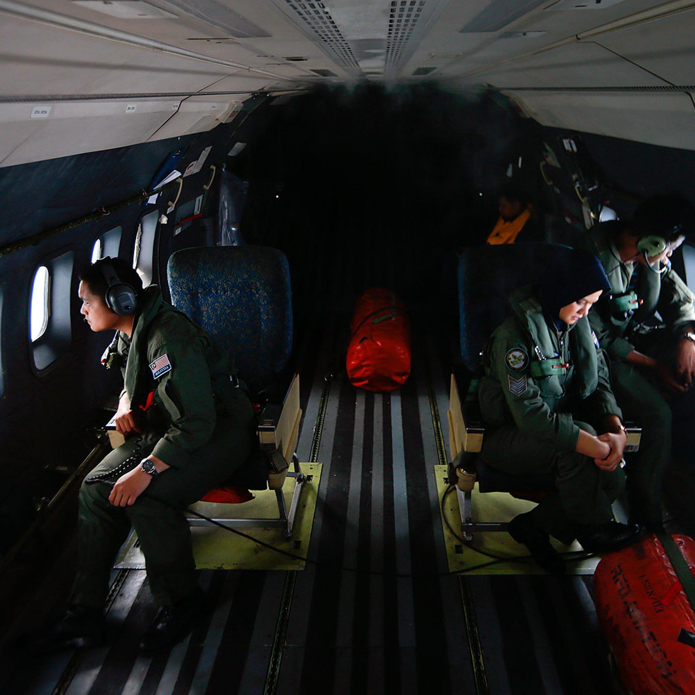 Crew members from the Royal Malaysian Air Force look through windows of a Malaysian Air Force CN235 aircraft during a Search and Rescue operation to find the missing Malaysia Airlines flight MH370, in the Straits of Malacca, March 13, 2014.