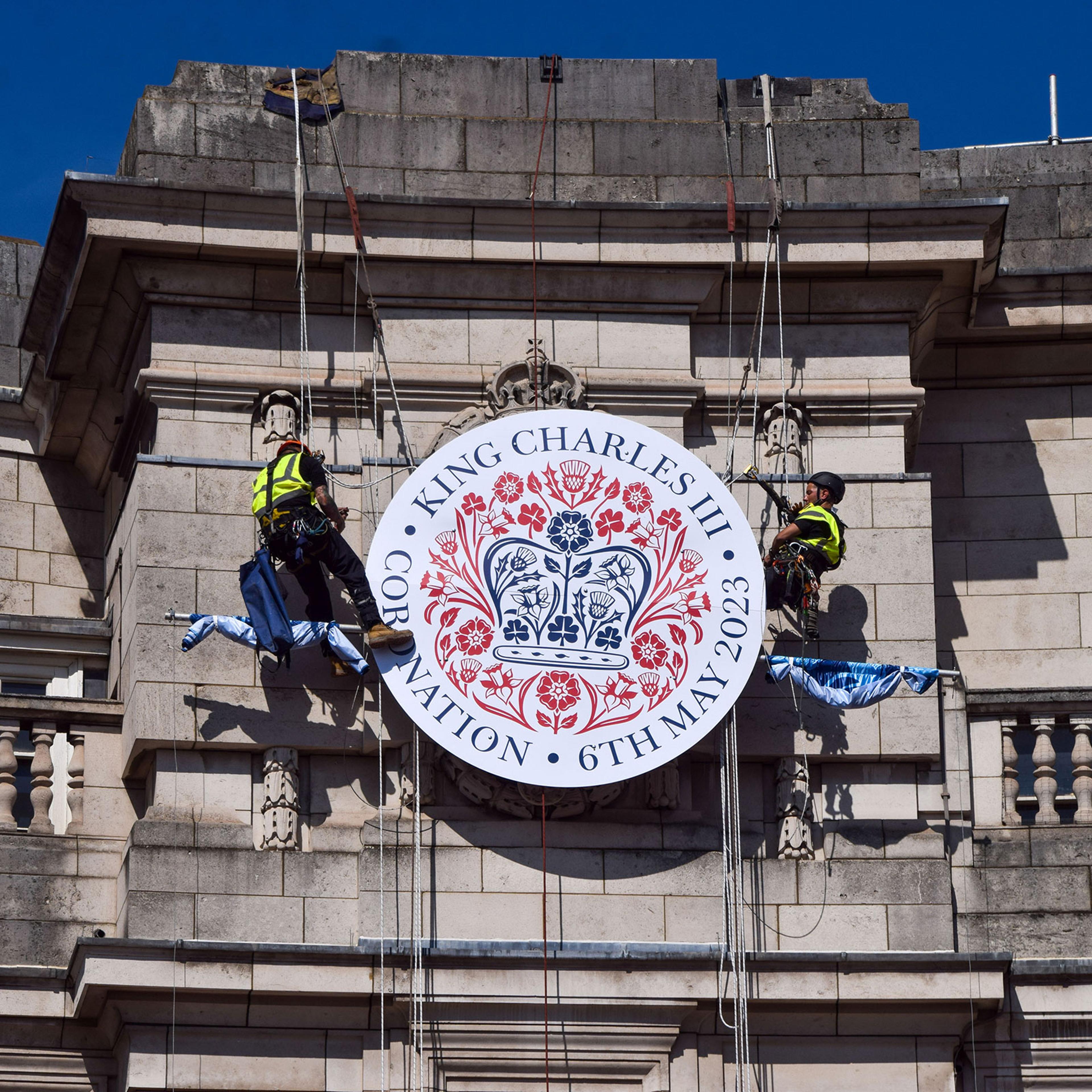 Workers install a huge coronation emblem on the Admiralty