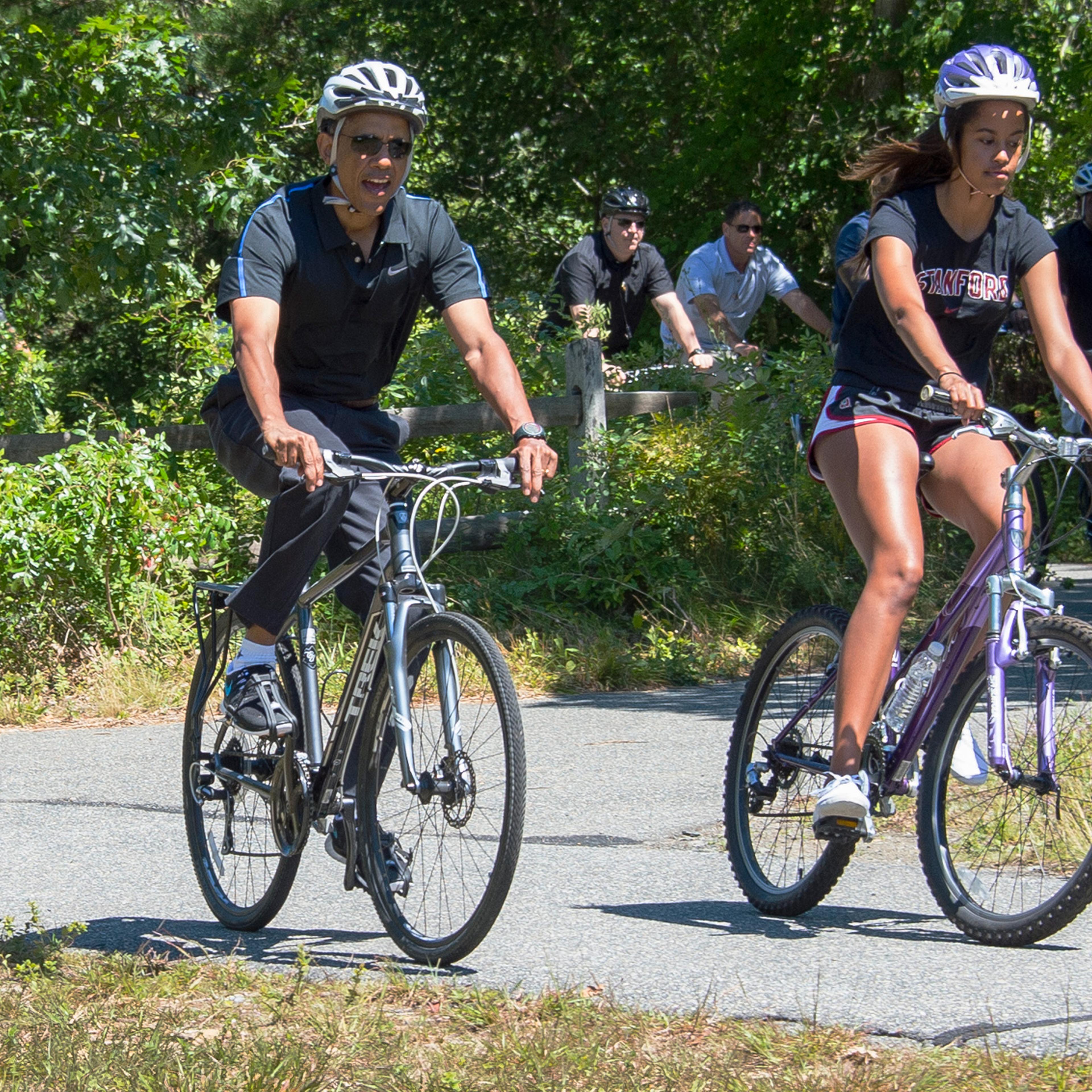 Aug. 15, 2014 President Barack Obama and daughter Malia Obama ride bikes along the Correllus State Bike Path outside of West Tisbury, Martha's Vineyard, Mass.