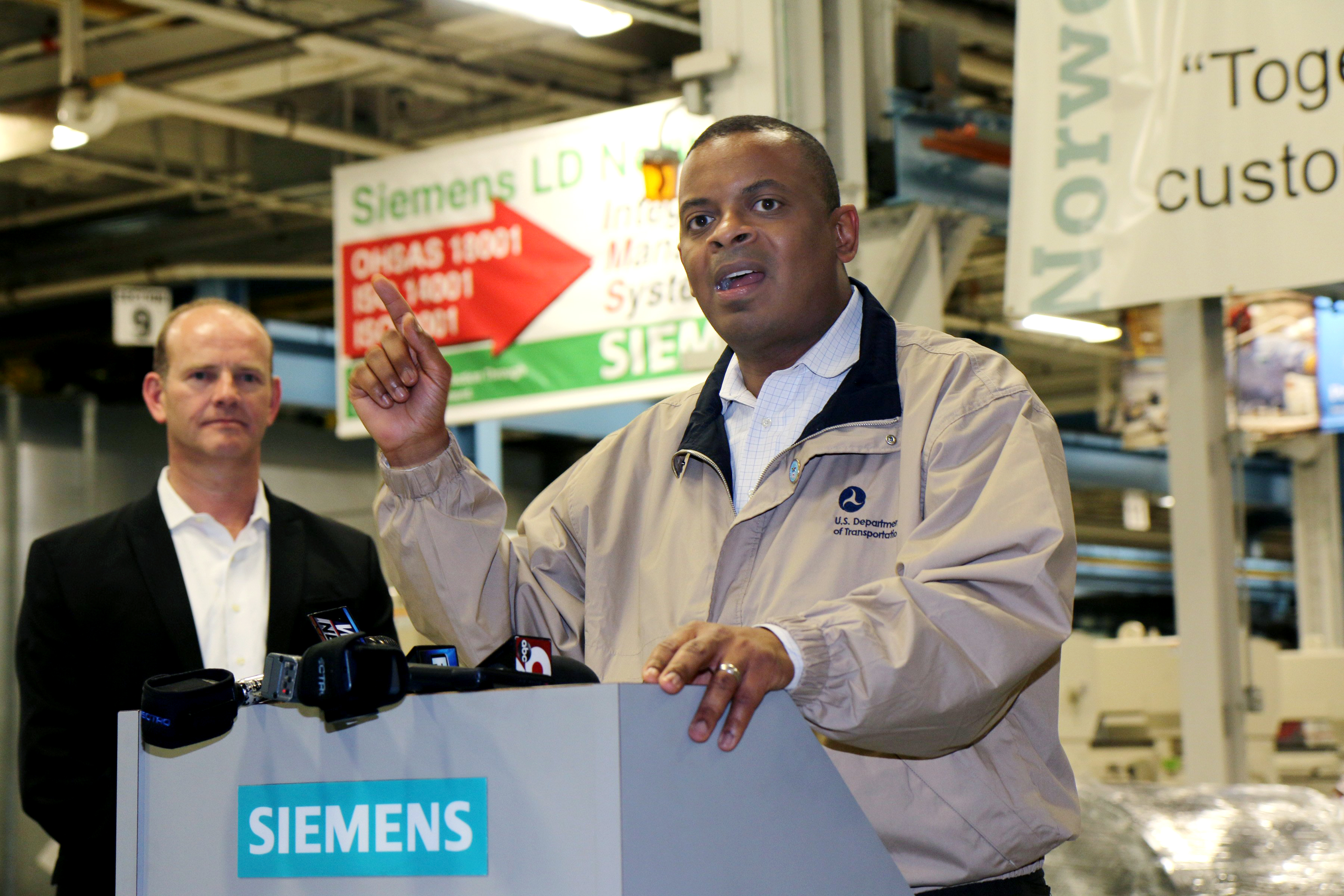 From left: Michael Cahill, President of Siemens Rail Systems in the U.S. listens to U.S. Transportation Secretary Anthony Foxx at the Siemens Motors Manufacturing Plant in Norwood, Ohio, April 14, 2014.